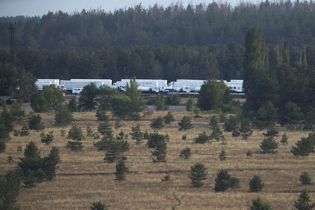 A convoy of white trucks with humanitarian aid park at the military base not far from Voronezh, Russia, Wednesday, Aug. 13, 2014. Russia on Wednesday dispatched some hundreds of trucks, although only a small proportion were counted in this convoy, covered in white tarps and sprinkled with holy water on a mission to deliver aid to a rebel-held zone in eastern Ukraine.