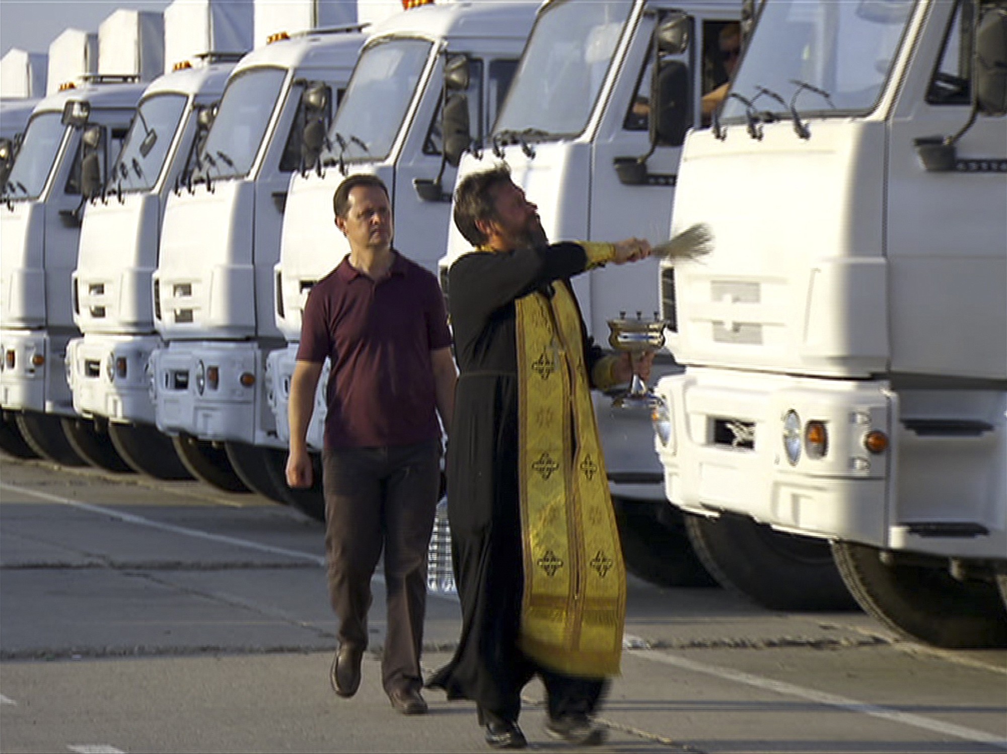 In this image taken from video, a Russian Orthodox Church clergyman blesses a convoy of white trucks with humanitarian aid in Alabino, outside Moscow on Tuesday.