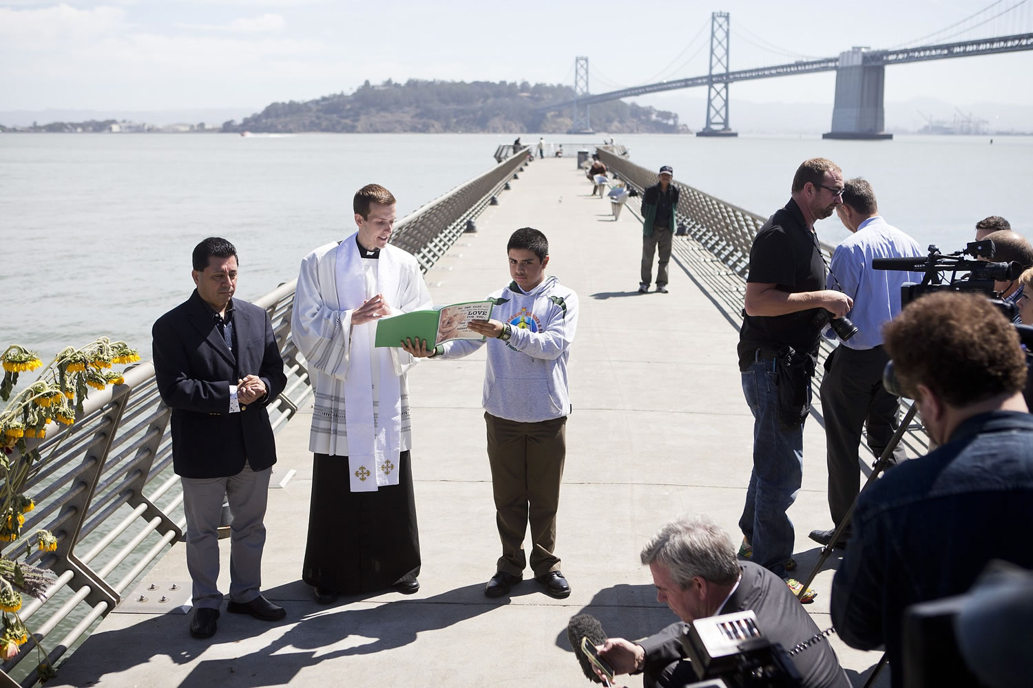 Father Cameron Faller, second left, of Restorative Justice Ministry conducts a vigil Monday for Kathryn Steinle on Pier 14 in San Francisco.