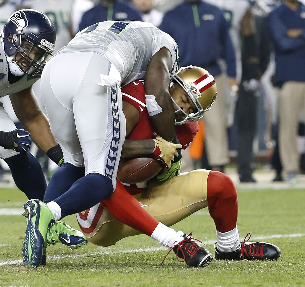 Seattle Seahawks strong safety Kam Chancellor, left, tackles San Francisco 49ers wide receiver Michael Crabtree during the first quarter on Thursday, Nov. 27, 2014.