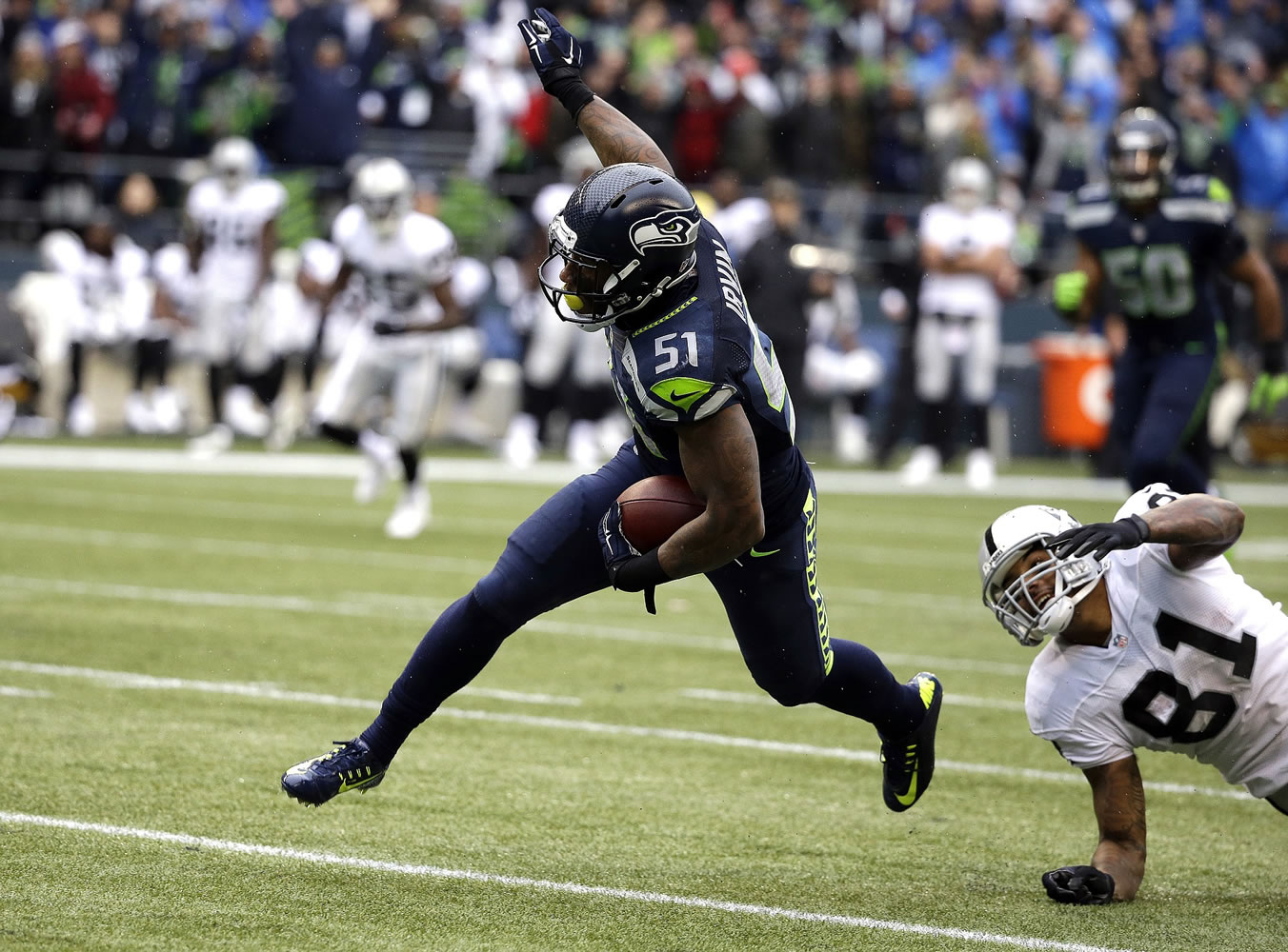 Seattle Seahawks outside linebacker Bruce Irvin (51) runs the ball as Oakland Raiders' Mychal Rivera (81) looks on after Irvin intercepted and ran for a touchdown in the first half of an NFL football game, Sunday, Nov. 2, 2014, in Seattle.