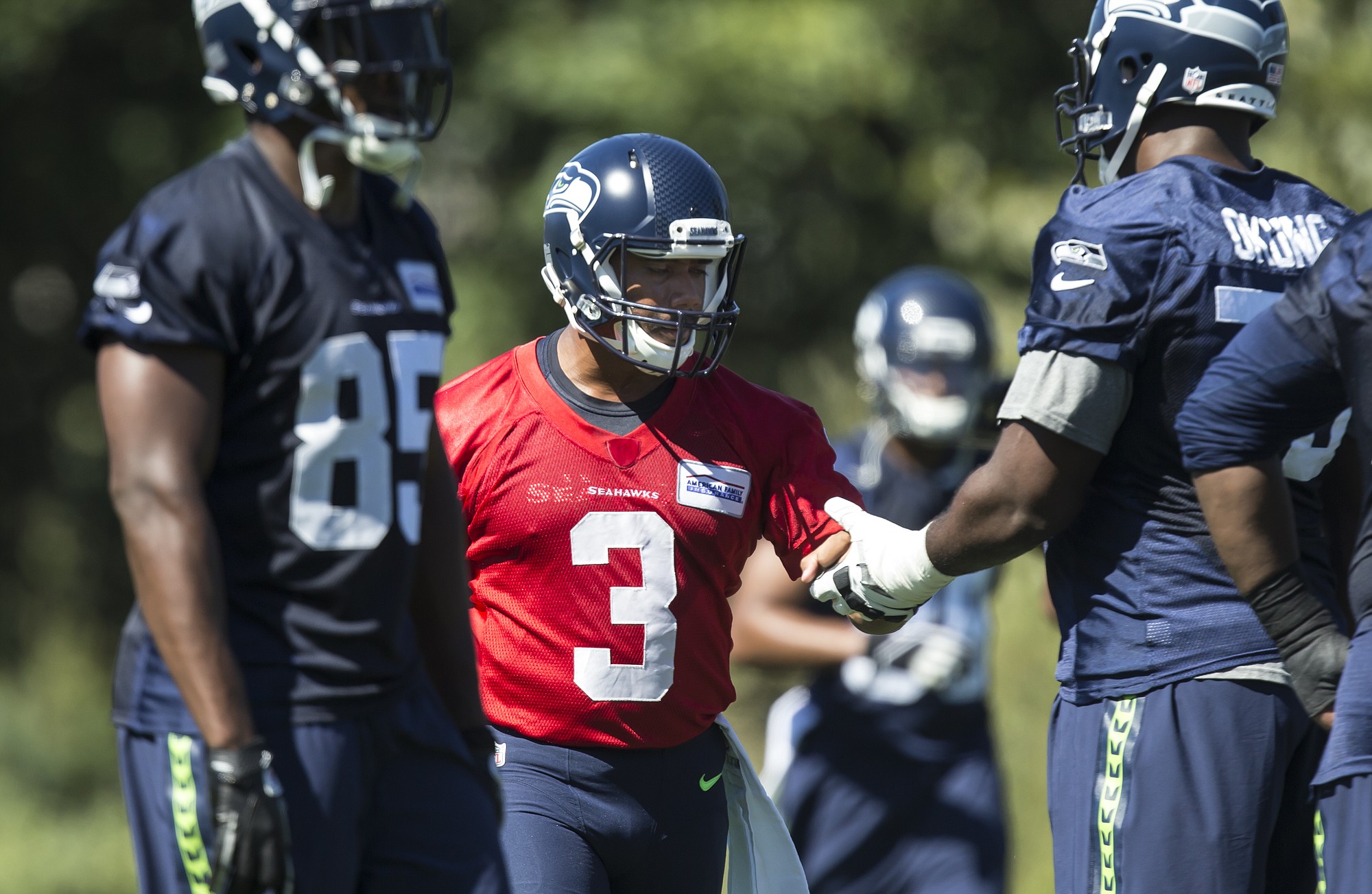 Seattle Seahawks quarterback Russell Wilson, center, shakes hands with offensive lineman Russell Okung during the first day of training camp on Friday, July 31, 2015, in Renton.
