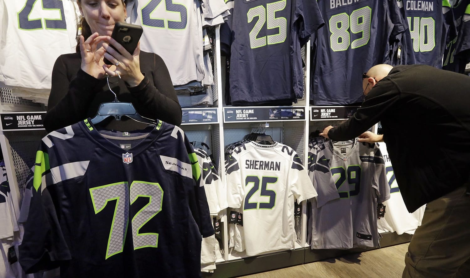 A couple of days out from the Seattle Seahawks winning the NFC championship on their way to the Super Bowl, Erin Rempel-Cheuk, left, calls her husband Tuesday in Seattle, to check on the jerseys he wants for he and his friends who will be attending the Super Bowl.