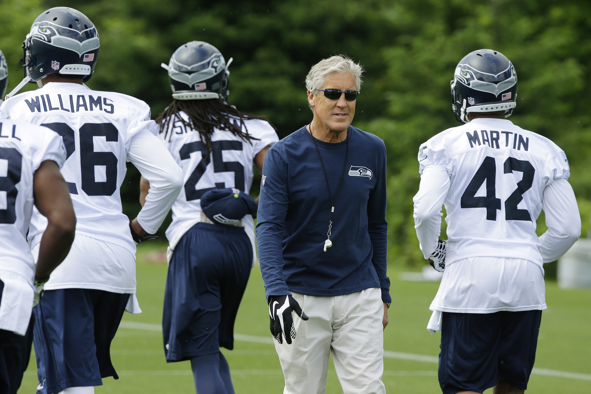 Seattle Seahawks head coach Pete Carroll walks by defensive players during Tuesday's organized team activity in Renton.
