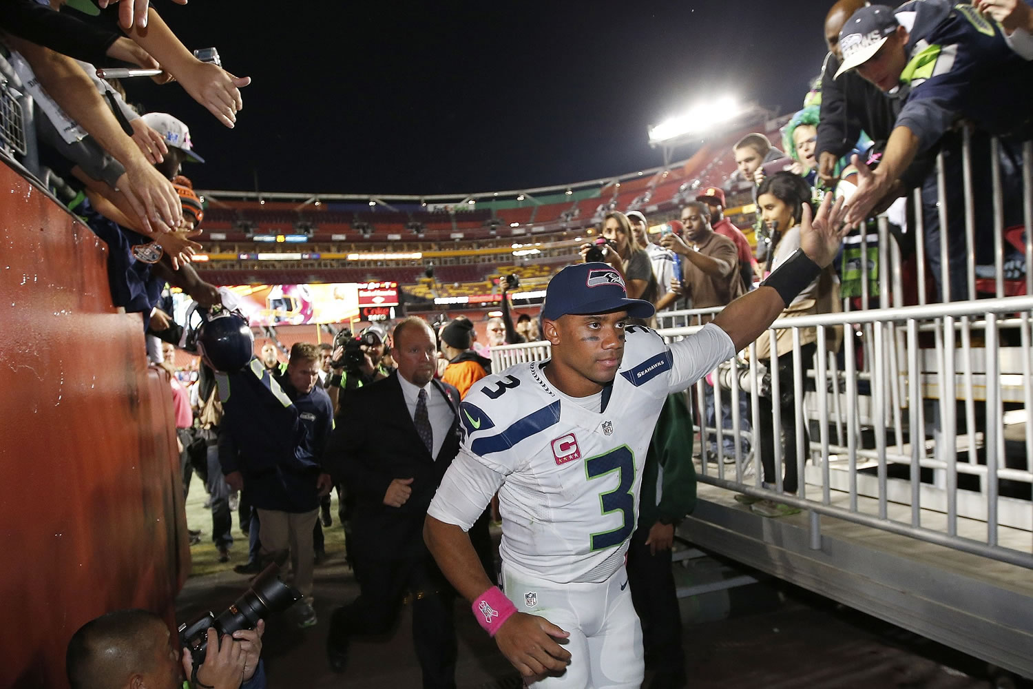 Seattle Seahawks quarterback Russell Wilson (3) reaches for the fans as he leaves the field  an NFL football game against the Washington Redskins in Landover, Md., Monday, Oct. 6, 2014. Seattle defeated Washington 27-17.