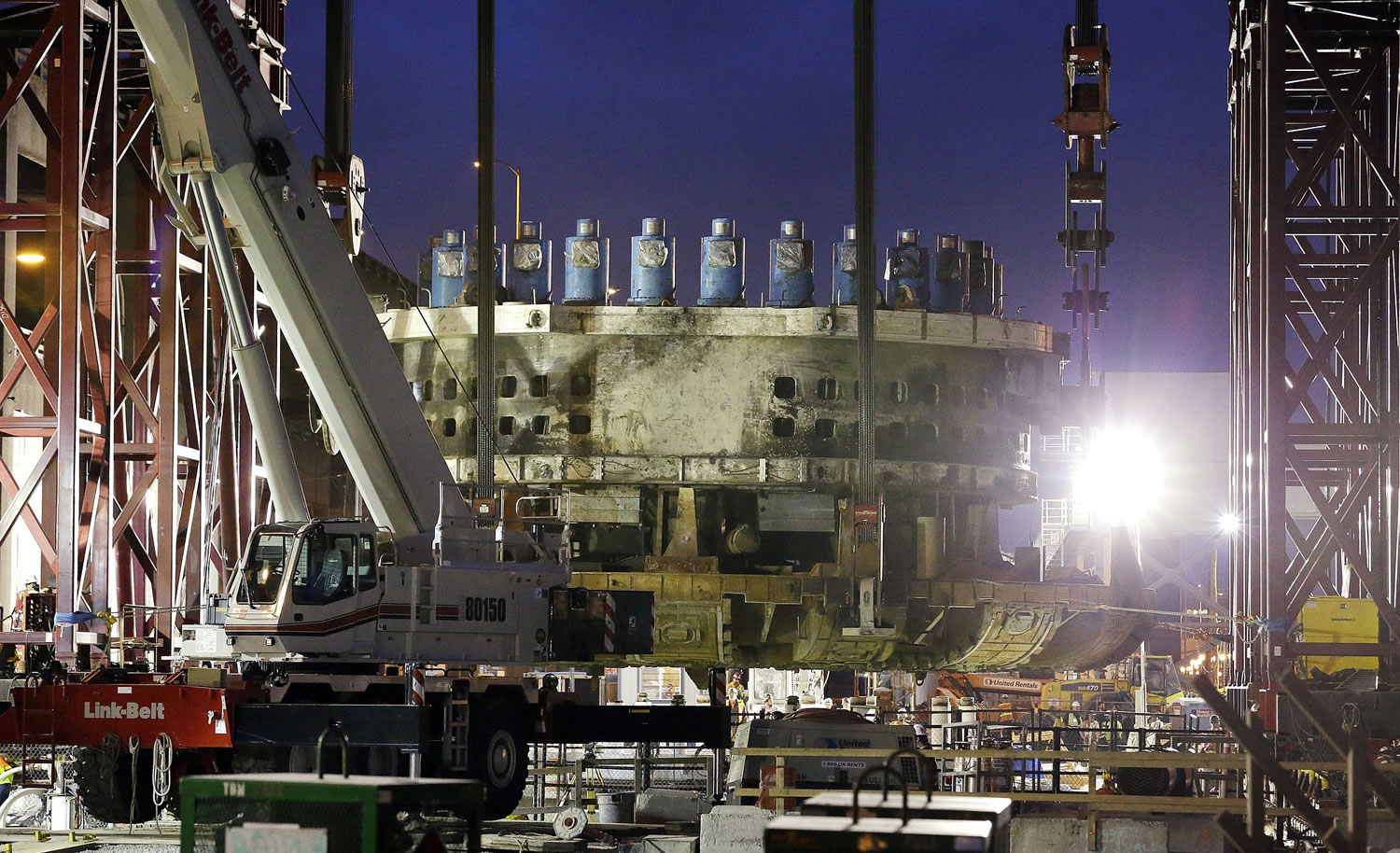 A 2,000-ton section of the broken tunnel boring machine known as Bertha is suspended horizontally above the pit it was pulled out of  March 30 in Seattle.