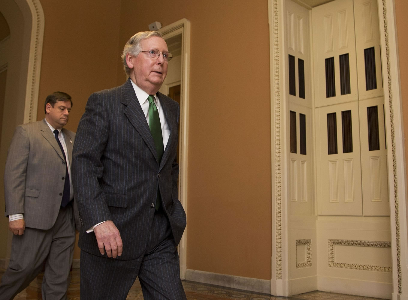 Senate Majority Leader Mitch McConnell, R-Ky., right, leaves the Senate floor on Capitol Hill in Washington, Monday, Feb. 23, 2015, following a cloture vote.