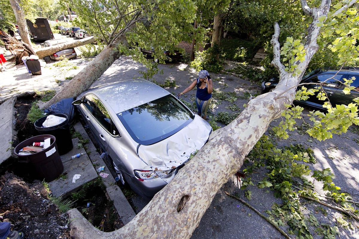 A woman inspects her damaged car in the aftermath of a storm Wednesday in Philadelphia.