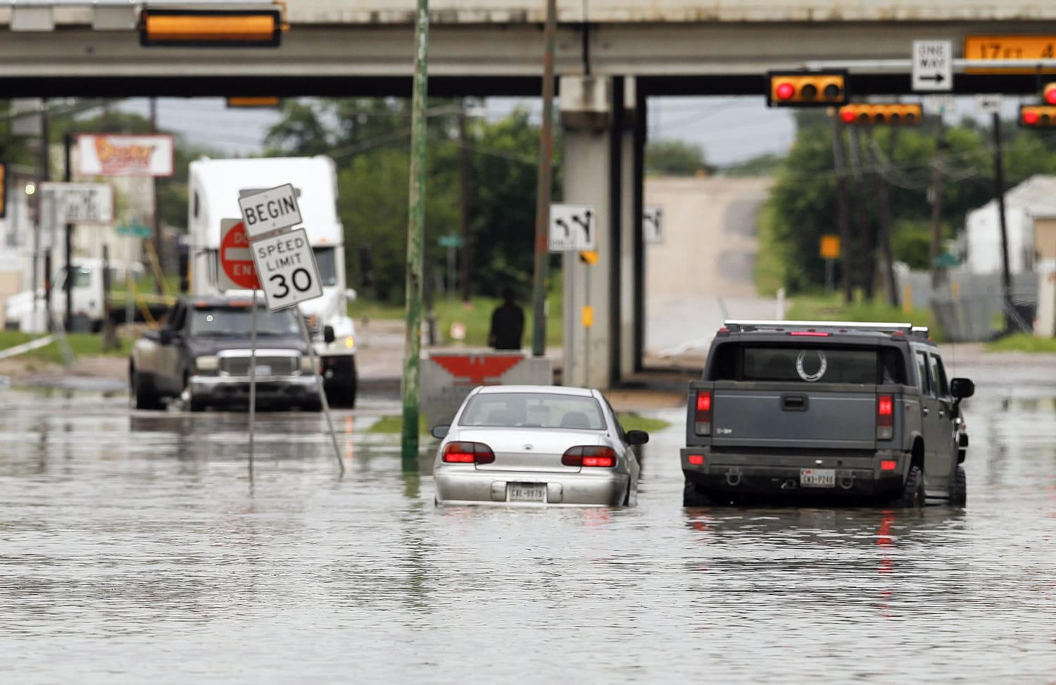 A motorist stops to help another driver stranded in high water in Dallas on Saturday.