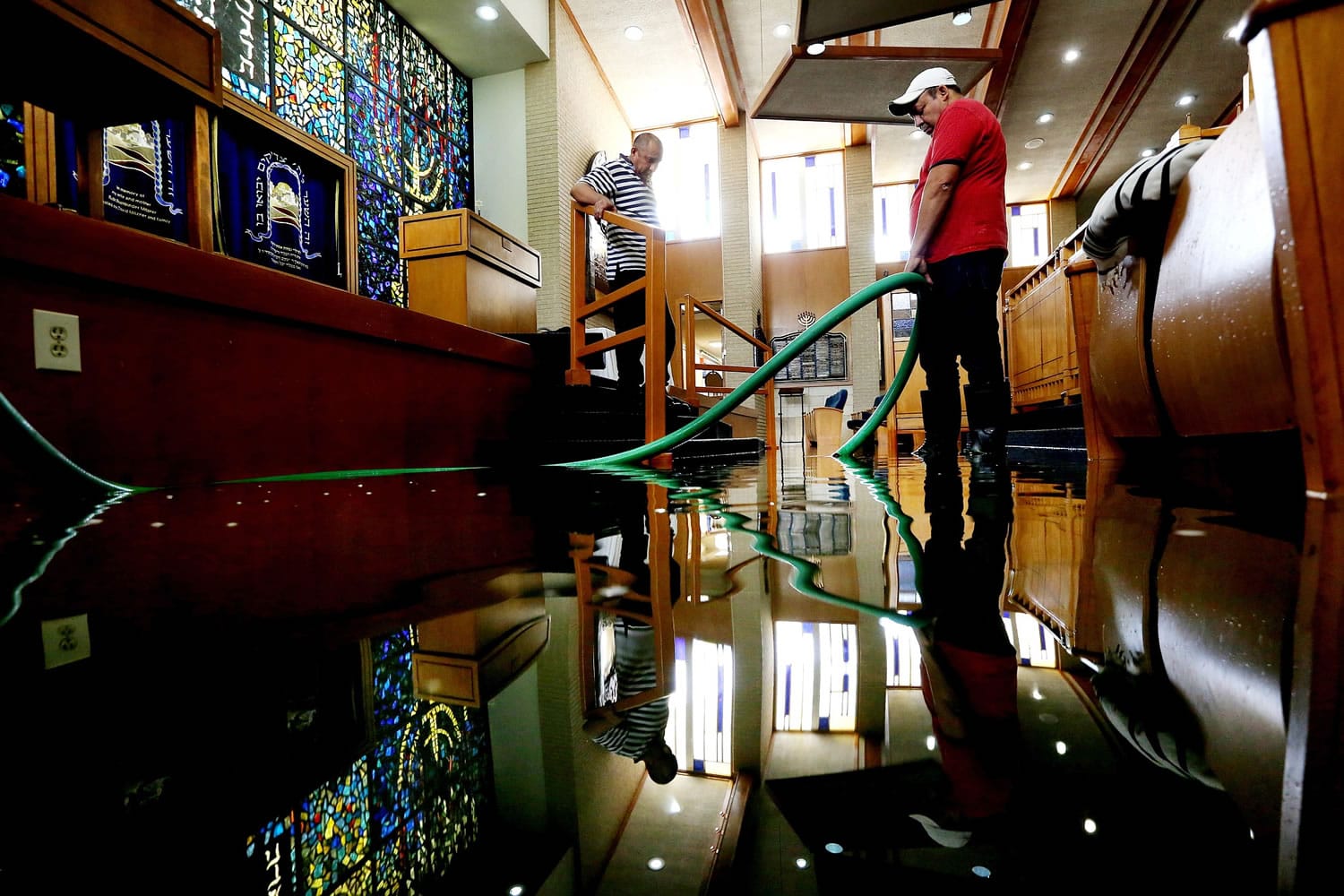 Wilber Albarenga, left, and Alfredo Chavez pump water Wednesday from the United Orthodox Synagogues of Houston, which sustained extensive flood damage.