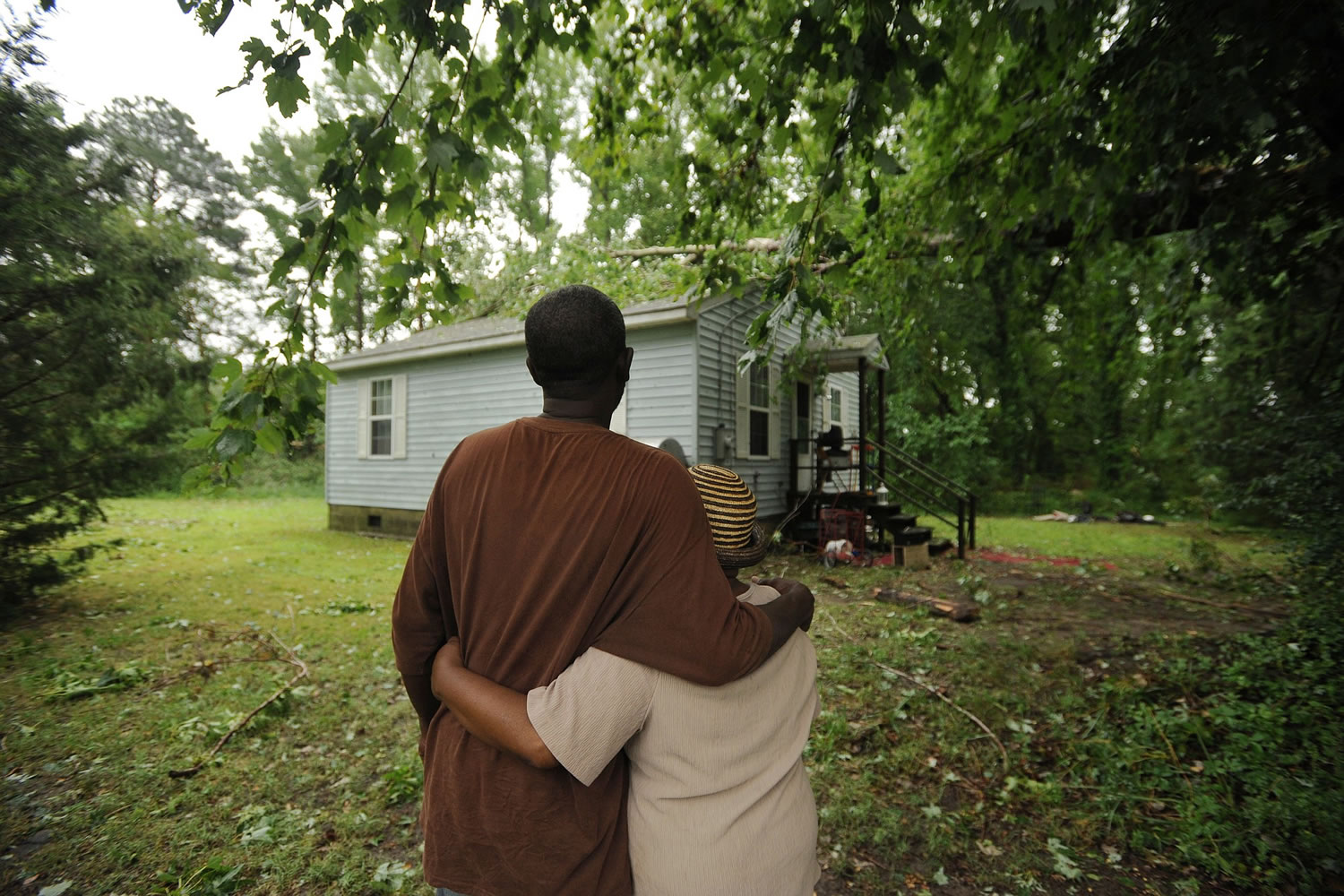 Marvin Brewer hugs his mother, Marva Stratton, as they look at a large tree that fell on the roof of her home in Cheriton, Va., when a severe storm passed through the area on Thursday.