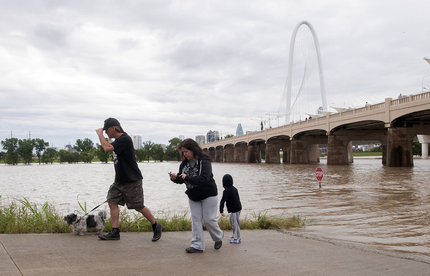 Curious onlookers walk along a closed path next to the Trinity River in Dallas on Saturday.