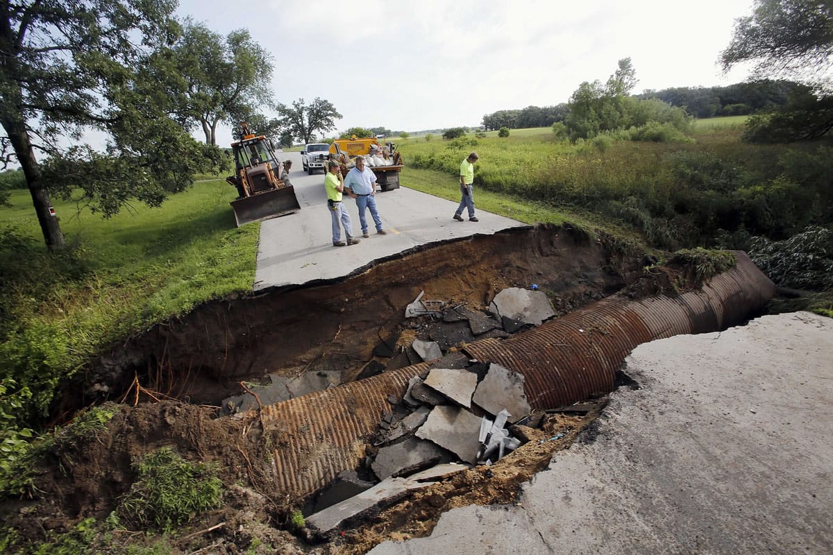 Kane County crews look over a sinkhole Tuesday in Burlington Township, Ill., where three people escaped serious injury when two vehicles traveled into the sinkhole on a rural stretch of road.