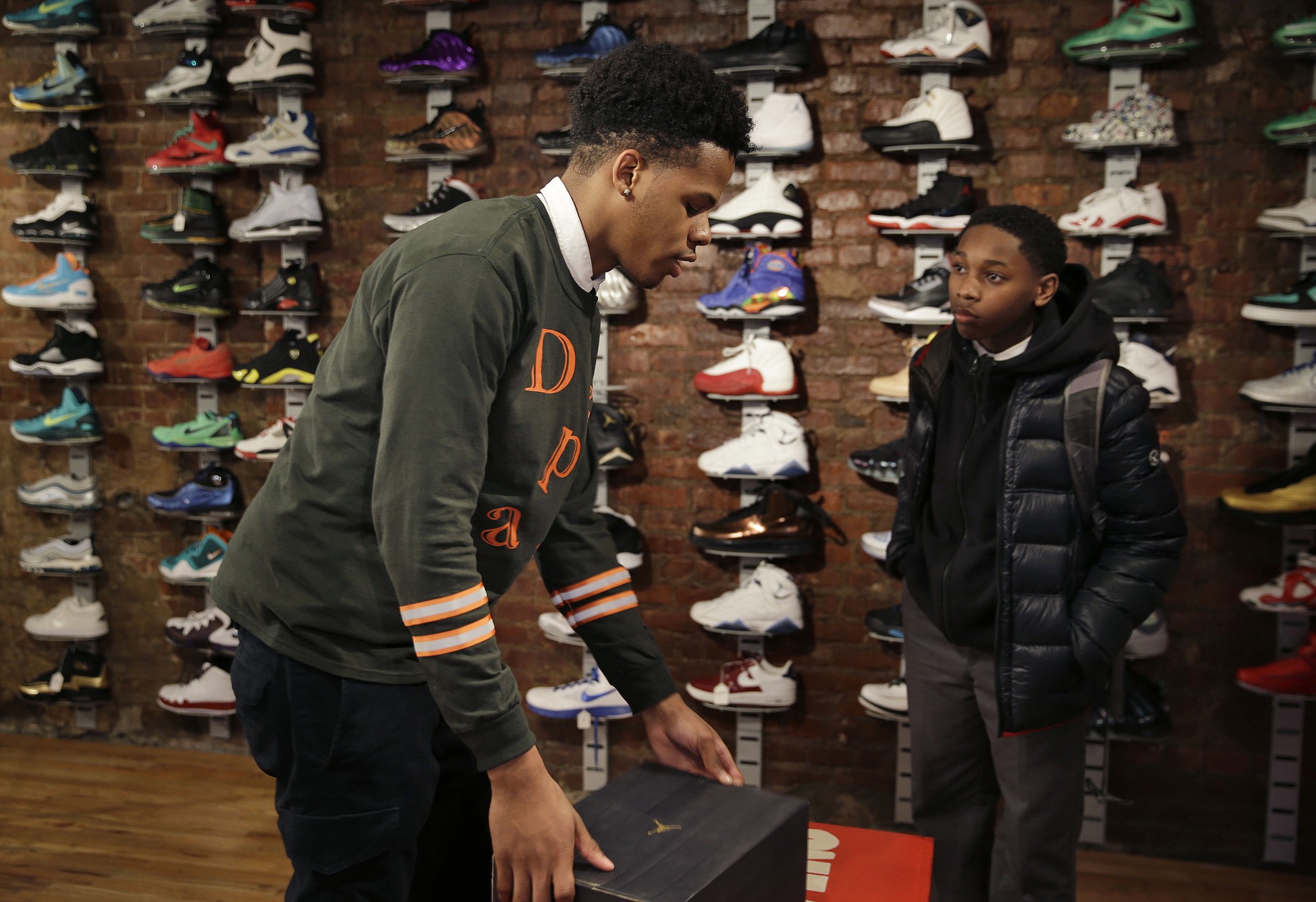 Chase Reed, left, boxes up a pair of shoes Monday for a customer, Chaise Mack, at Sneaker Pawn in the Harlem section of New York. Chase and his father opened Sneaker Pawn looking to capitalize on America's multi-billion dollar athletic footwear market.