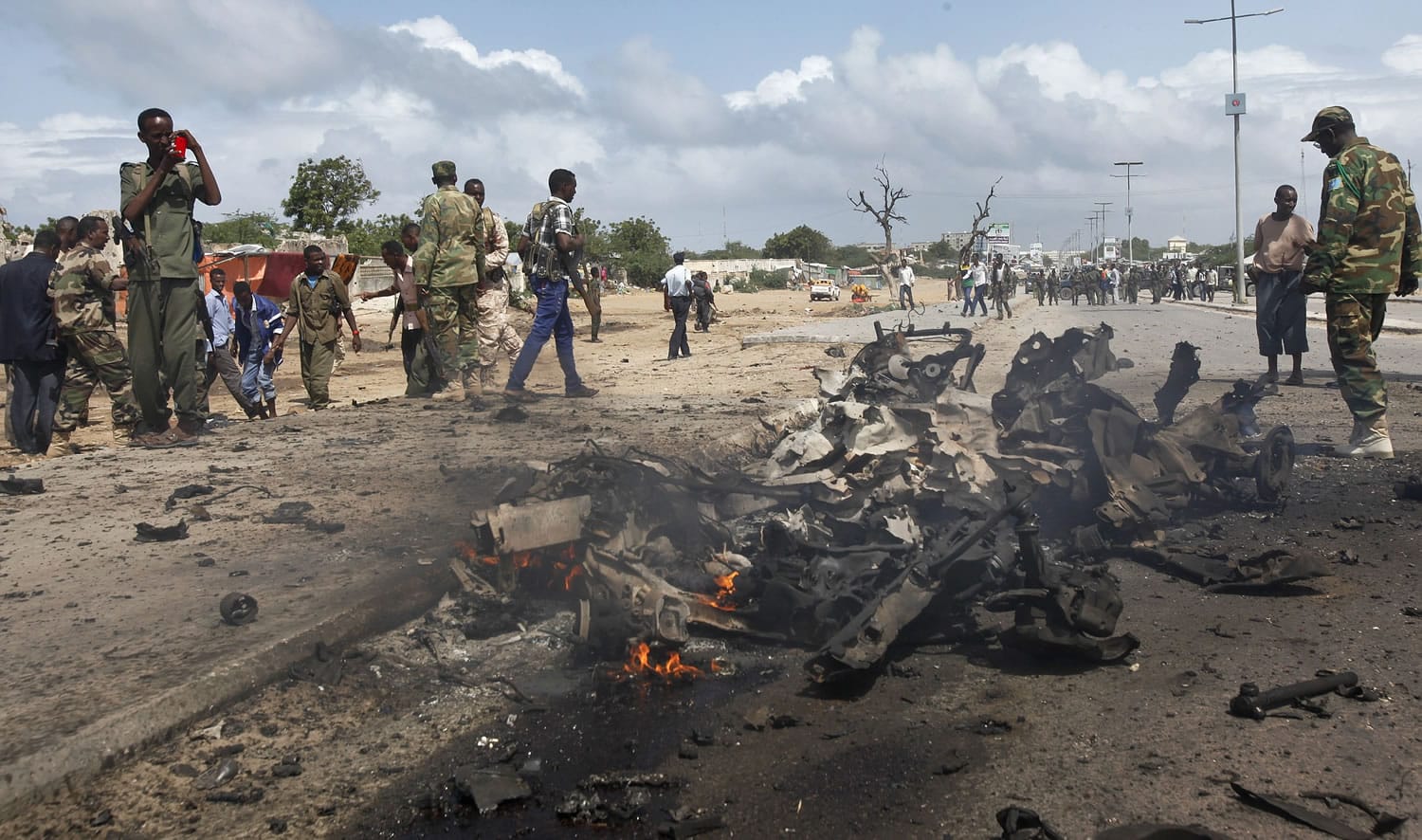 Somali soldiers stand near the wreckage at the scene of a suicide car bomb attack which targeted a convoy of foreign officials, in Mogadishu, Somalia, on Wednesday.