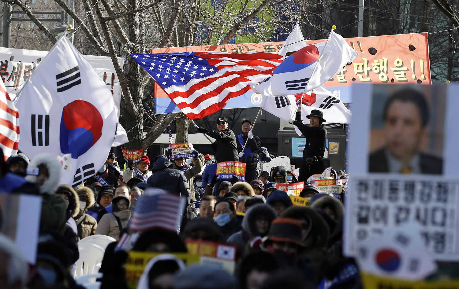 People wave the flags of South Korea and the United States during a rally Tuesday denouncing the attack on U.S.