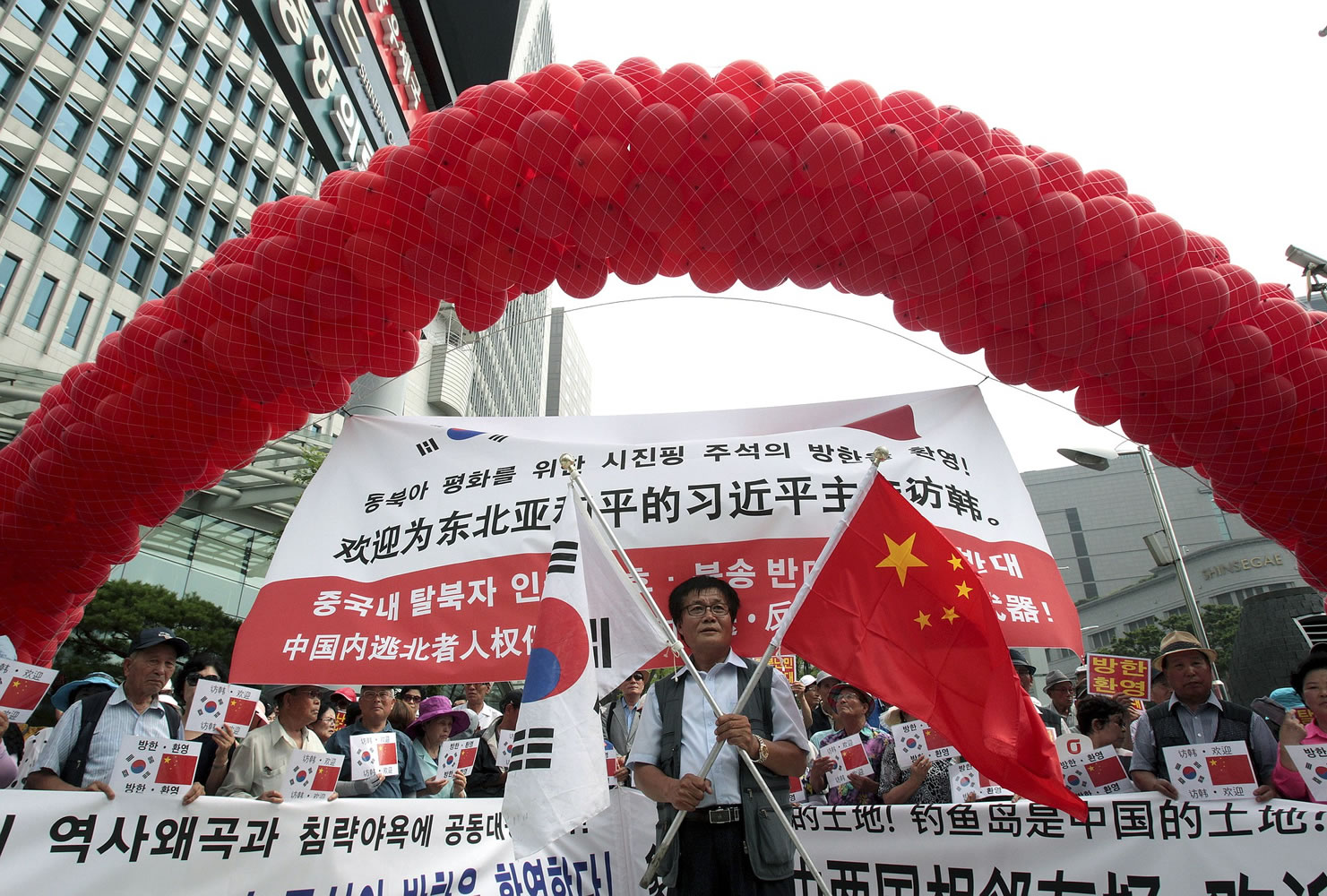A conservative activist holds a South Korean and Chinese national flag during a rally welcoming Chinese President Xi Jinping's visit to  South Korea, near the Chinese Embassy in Seoul, South Korea, on Wednesday.
