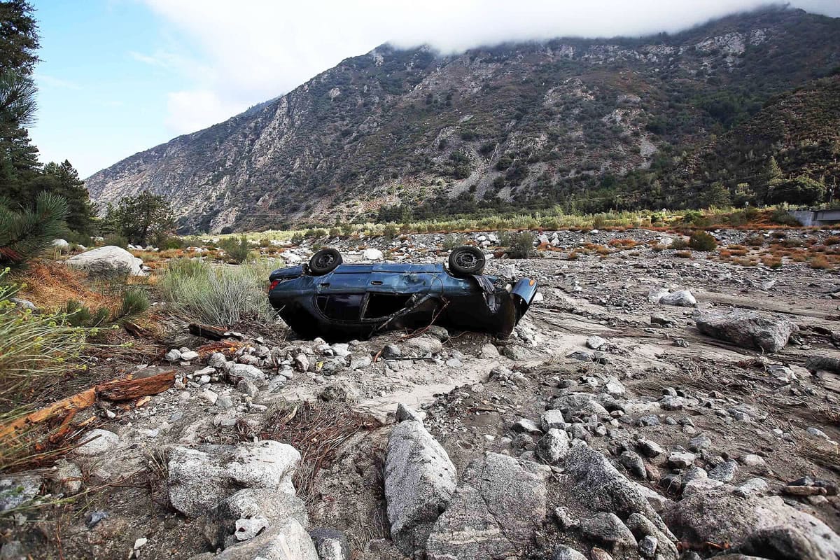 A car lies where it was swept down a wash in the mountain community of Forest Falls in the San Bernardino Mountains Monday, Aug. 4, 2014. Crews cleared roads in an area where some 2,500 had been stranded after thunderstorms caused mountain mudslides in Southern California over the weekend, while authorities estimated that between six and eight homes were badly damaged and likely uninhabitable. One person was found dead in a vehicle that was caught in a flash flood. A group of campers spent the night at a community center near Forest Falls.