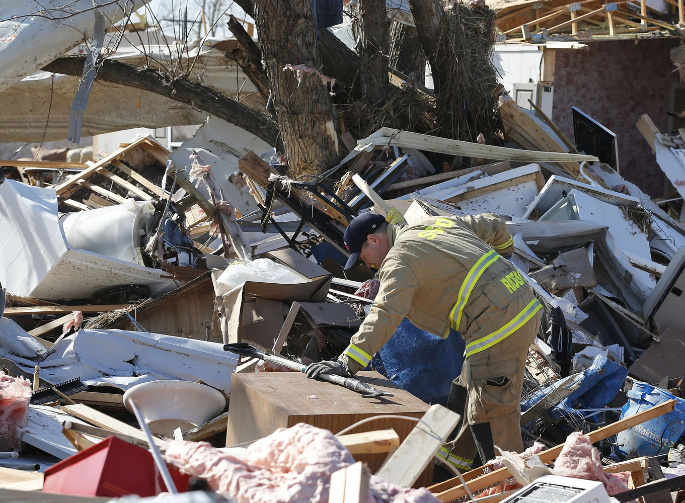 Dugan Ridenour of the Sand Springs fire department digs through rubble in the tornado-damaged River Oaks Estates mobile home park in Sand Springs, Okla., on Thursday.