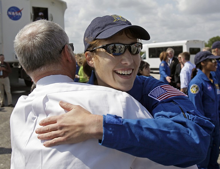 Space shuttle Discovery mission specialist Dottie Metcalf-Lindenburger gets a hug from NASA launch director Pete Nicolenko, after landing Tuesday at Kennedy Space Center in Cape Canaveral, Fla. At top, Discovery touches down on Kennedy Space Center's Runway 33.