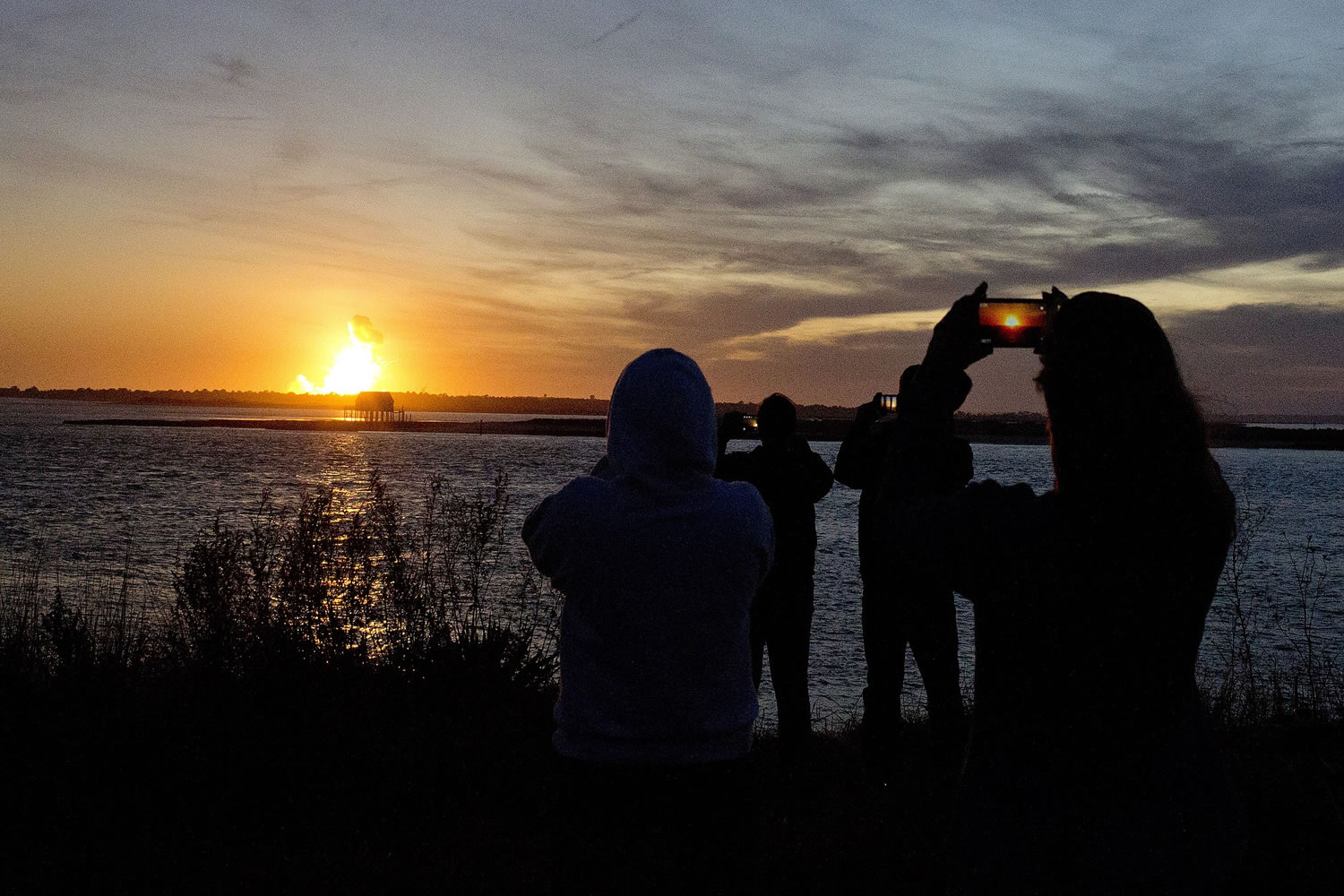 Spectators in Chincoteague, Va., watch the fireball from the explosion of the unmanned Orbital Sciences Corp.'s Antares rocket and Cygnus cargo capsule seconds after liftoff from Wallops Island, Va.