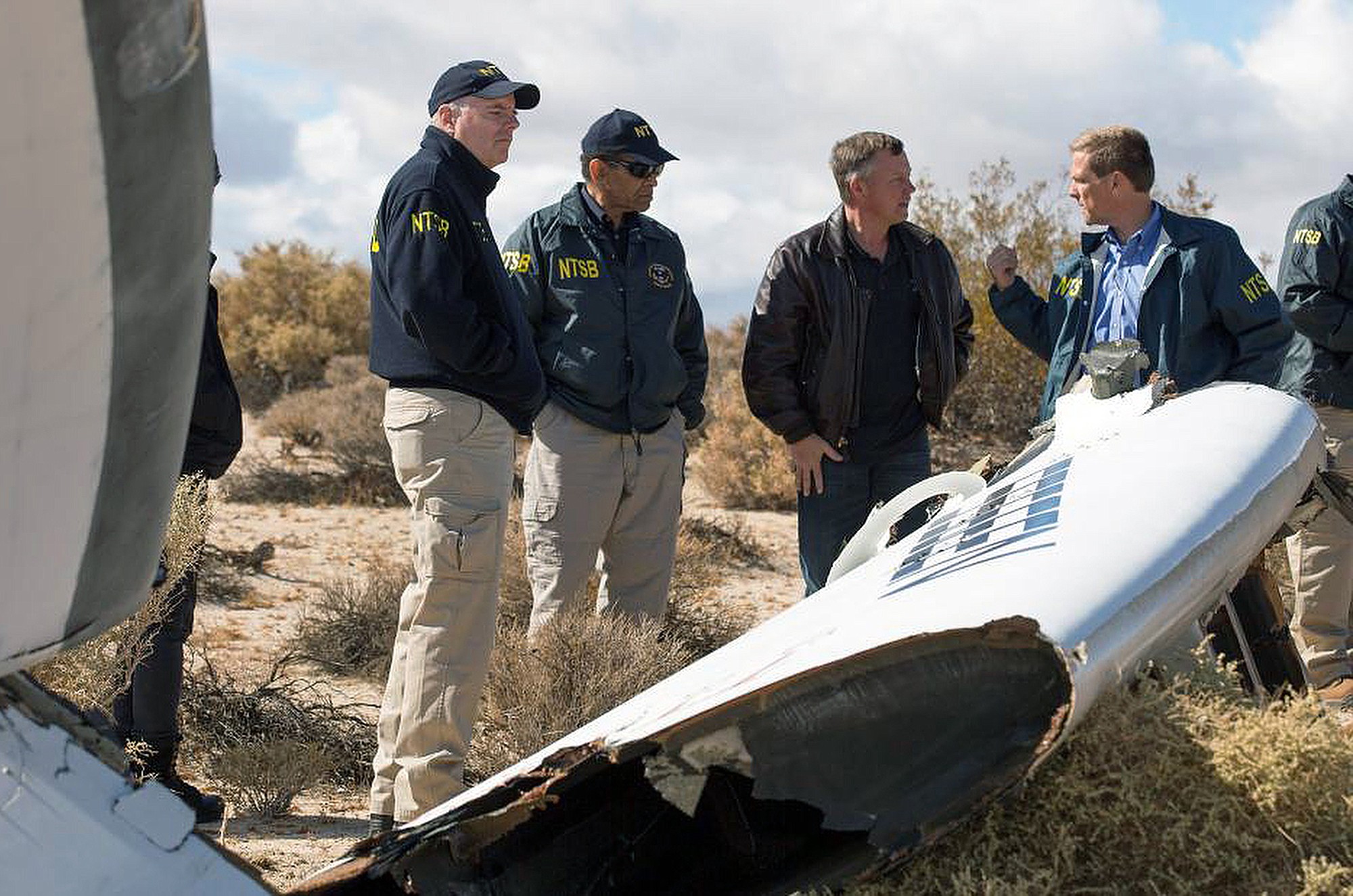 Virgin Galactic pilot Todd Ericson, right, talks with NTSB Acting Chairman Christopher A. Hart, second from left, at the SpaceShipTwo accident site with investigators in Mojave, Calif.