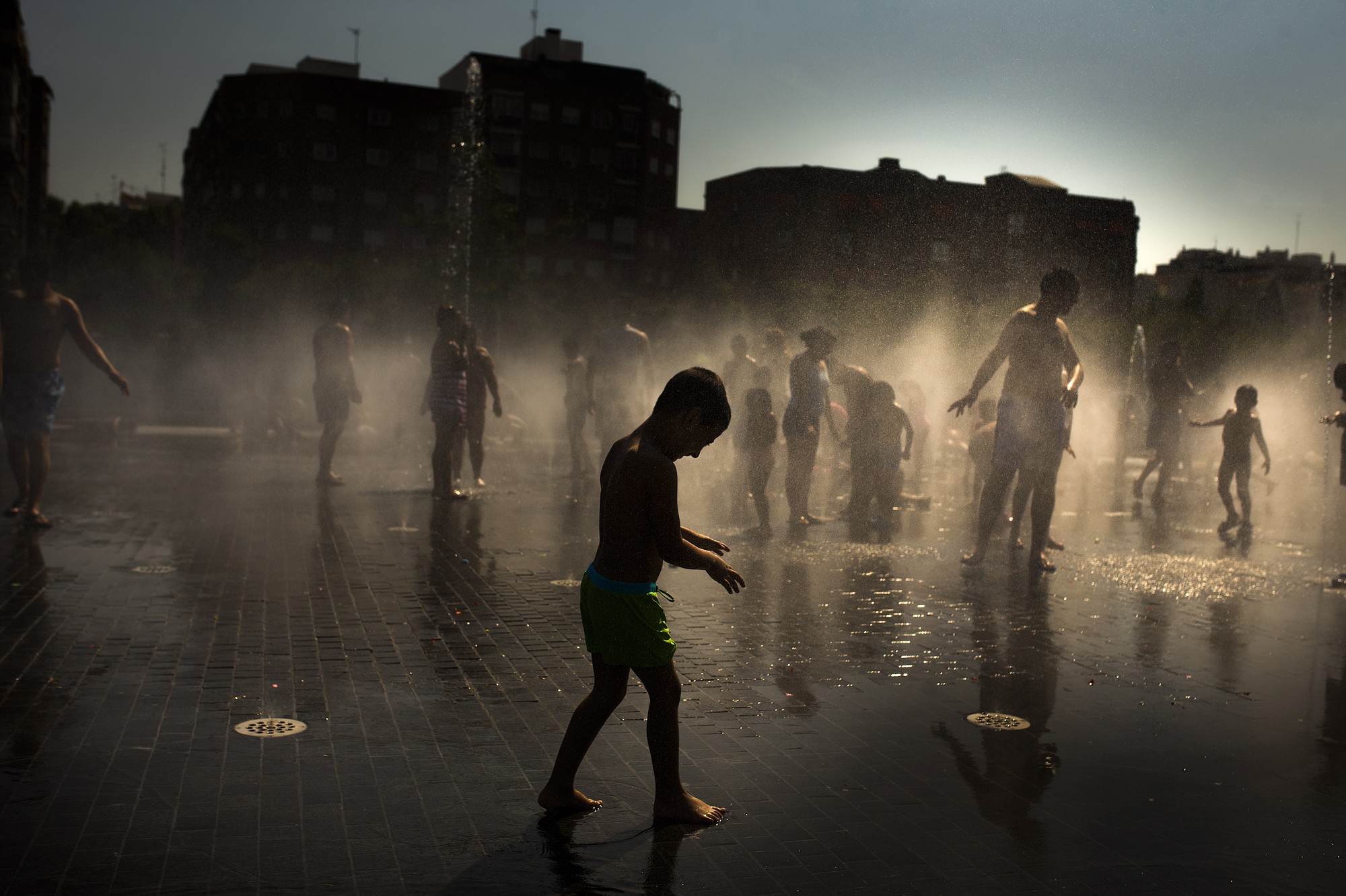 Children play as they cool down in a fountain beside Manzanares river in Madrid,  Spain, on Sunday.