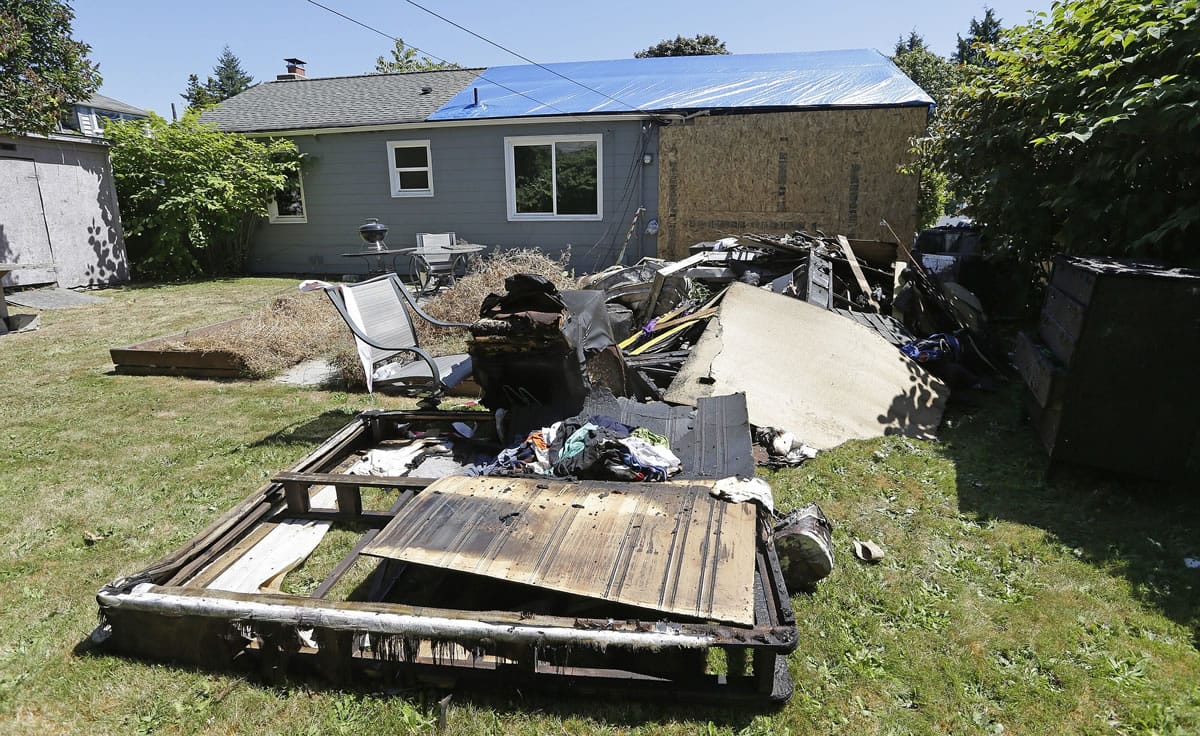 Debris from a fire fills the backyard of a boarded-up Seattle house Wednesday. The night before, a resident had used a can of spray paint and a lighter as a makeshift blowtorch to kill a spider, starting a blaze that caused $60,000 worth of damage, Seattle fire officials said.