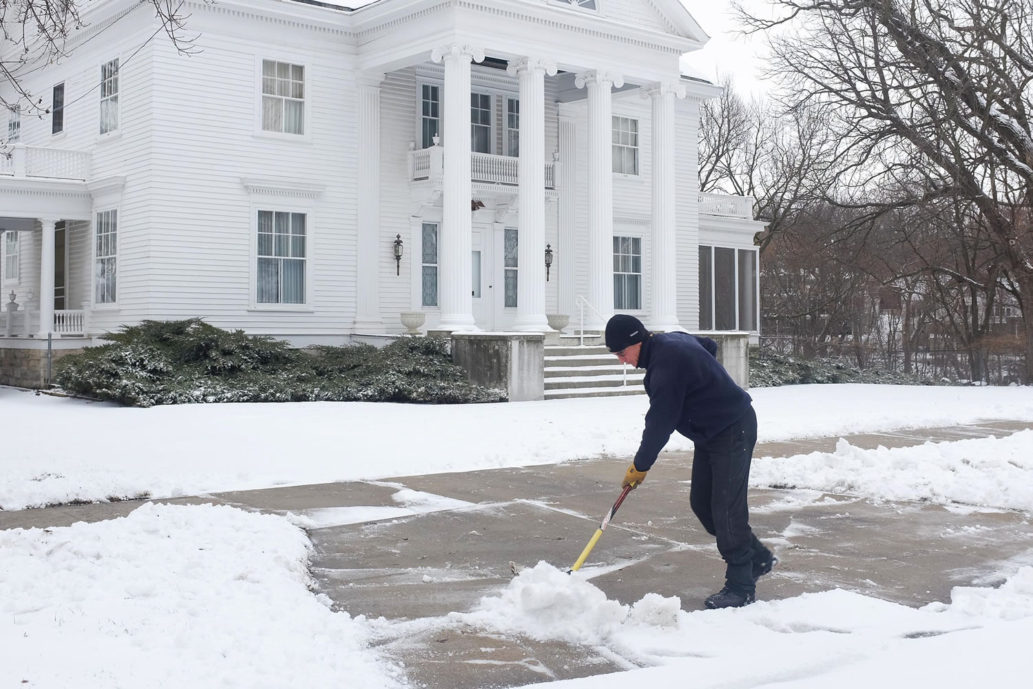 Al Searle shovels late-season snow Monday in Mason City, Iowa.