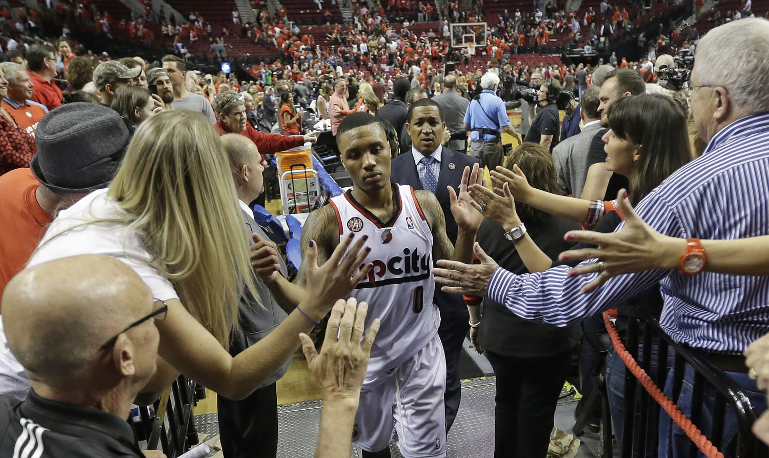 Portland Trail Blazers' Damian Lillard (0) walks off the court as fans reach for him following Game 4 of a Western Conference semifinal NBA basketball playoff series against the San Antonio Spurs, Monday, May 12, 2014, in Portland, Ore. The Trail Blazers won 103-92.