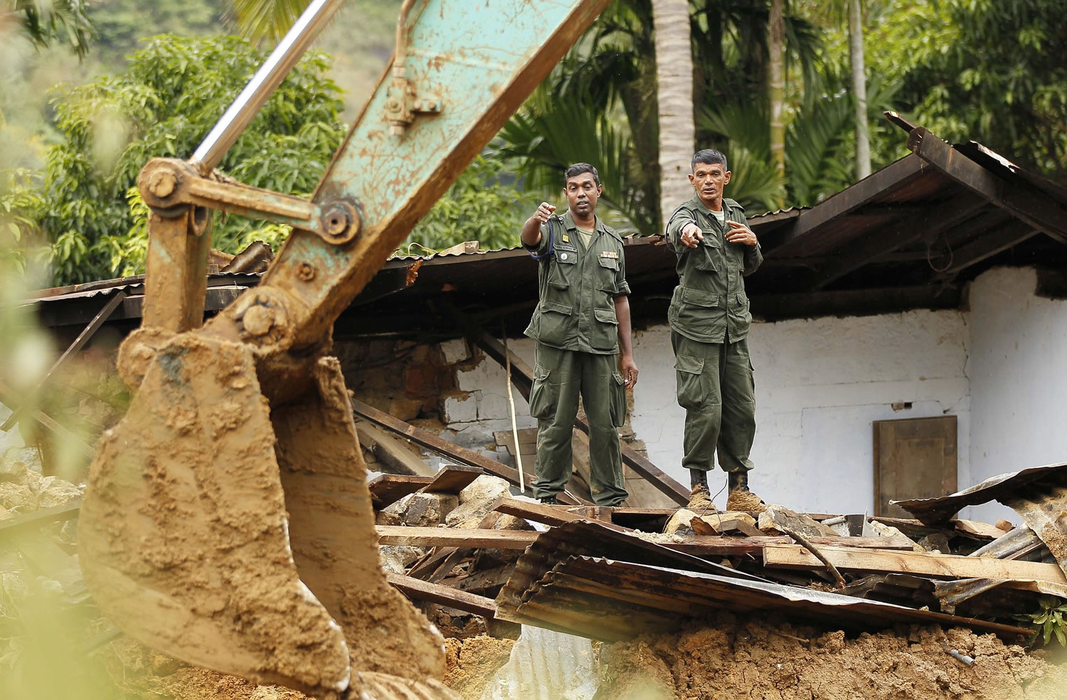 Sri Lankan army soldiers direct an excavator clearing debris Friday at the site of a mudslide in at the Koslanda tea plantation in Badulla district, about 140 miles east of Colombo, Sri Lanka. Disaster officials estimate that about 100 people were killed Wednesday morning when monsoon rains unleashed a cascade of muddy earth at the plantation and warned of more landslides at the area.