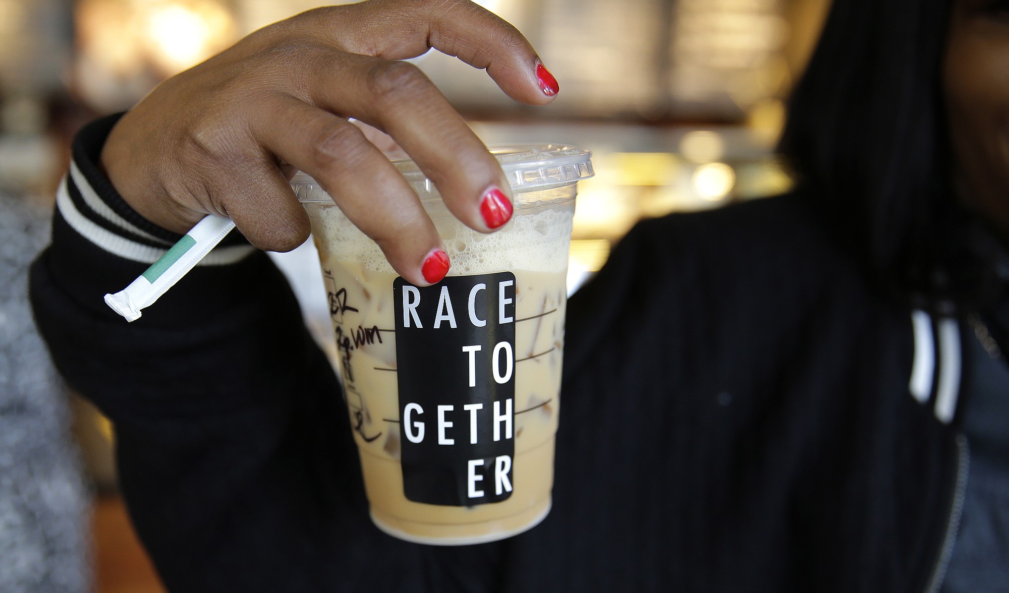 Larenda Myres holds an iced coffee drink with a &quot;Race Together&quot; sticker on it March 18 at a Starbucks store in Seattle.