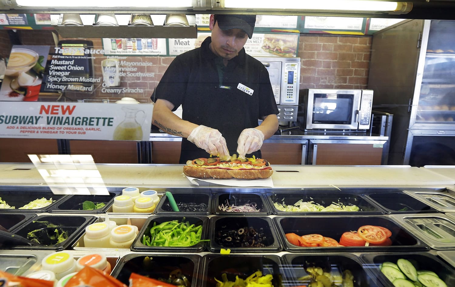 Roberto Castelan makes a sandwich at a Subway sandwich franchise in Seattle.