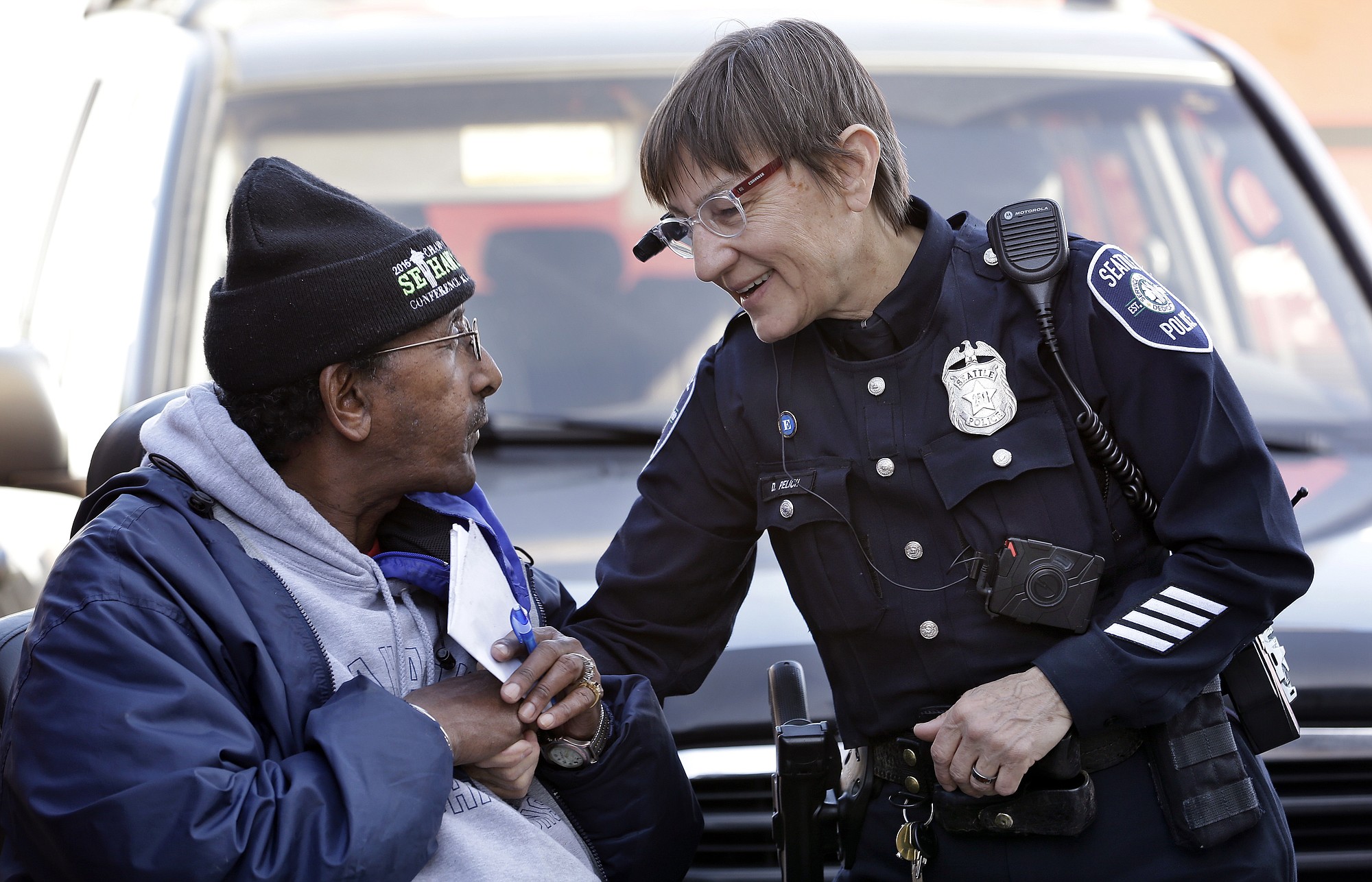 Seattle police officer Debra Pelich, right, wears a video camera on her eyeglasses as she talks Thursday with Alex Legesse before a small community gathering in Seattle.