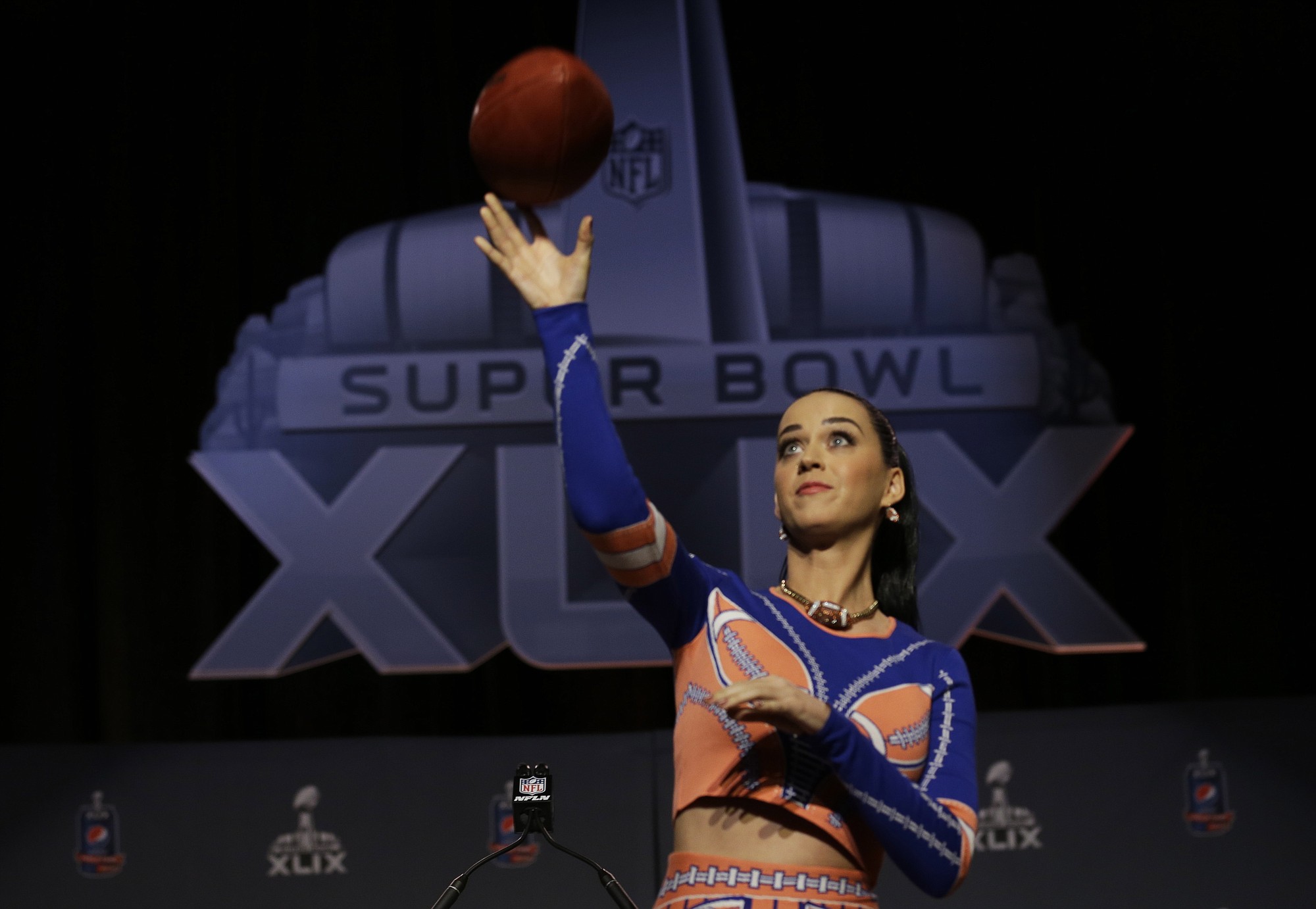 Katy Perry throws a football at a news conference for NFL Super Bowl XLIX Thursday in Phoenix.
