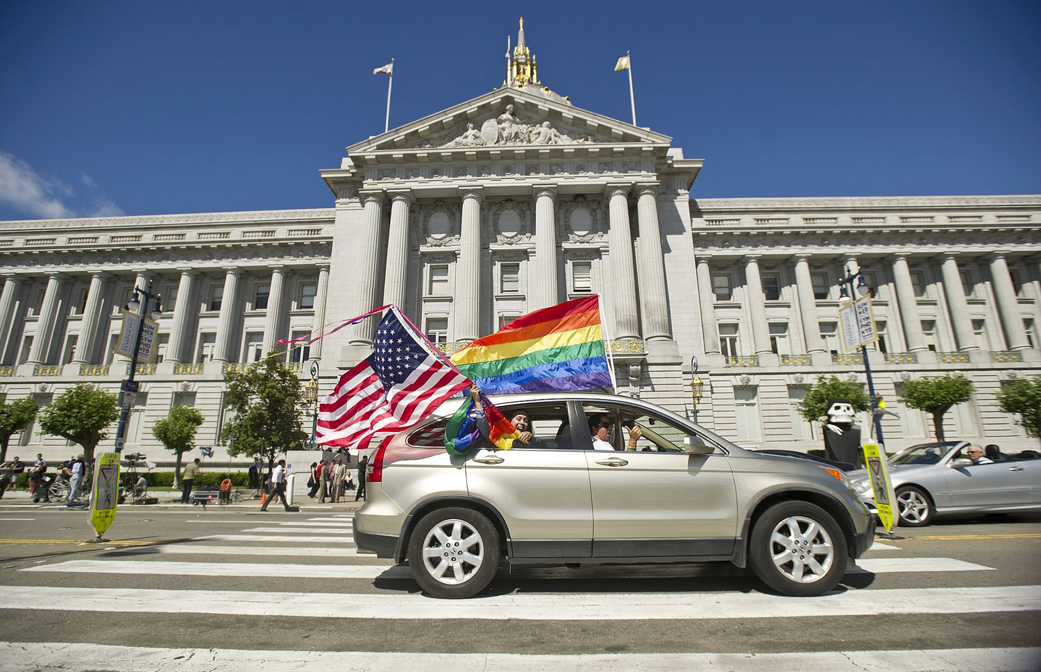 Revelers drive past San Francisco City Hall waving rainbow flags and an American flag on Wednesday shortly after the U.S.