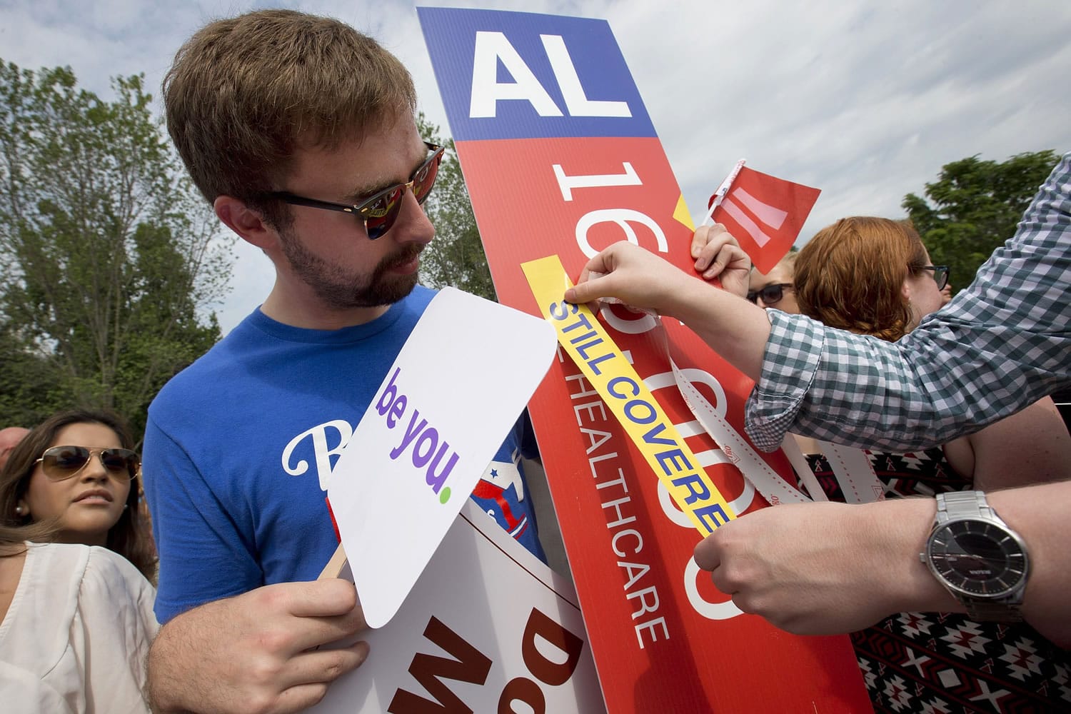 Trent Seubert, left, holds a sign stating that 165,000 people would lose healthcare coverage, as the words &quot;lose healthcare&quot; are covered over with a &quot;still covered&quot; sticker outside the Supreme Court in Washington on Thursday after the court decided that the without the Affordable Care Act (ACA) may provide nationwide tax subsidies.