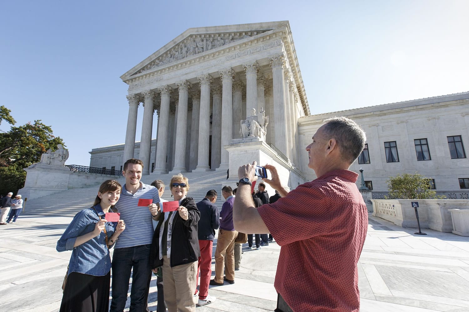 Stephen Kirby, right, takes a souvenir photo of his family holding visitor tickets as the Supreme Court begins its new term Oct.