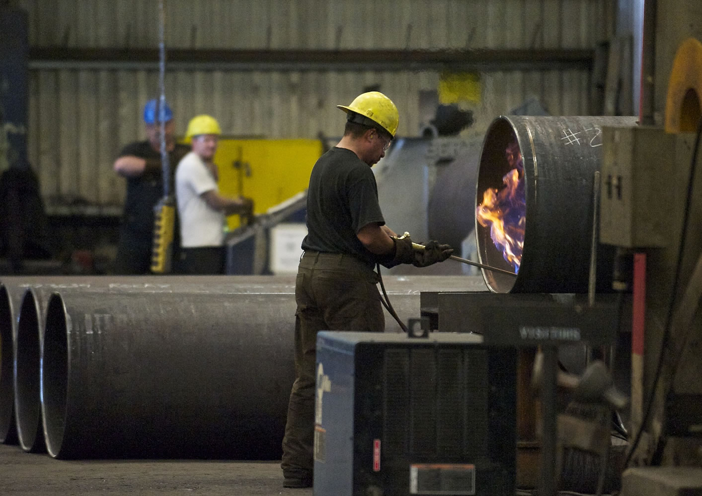 An employee fires up a torch inside the Thompson Metal Fab facility during a tour in July 2013.