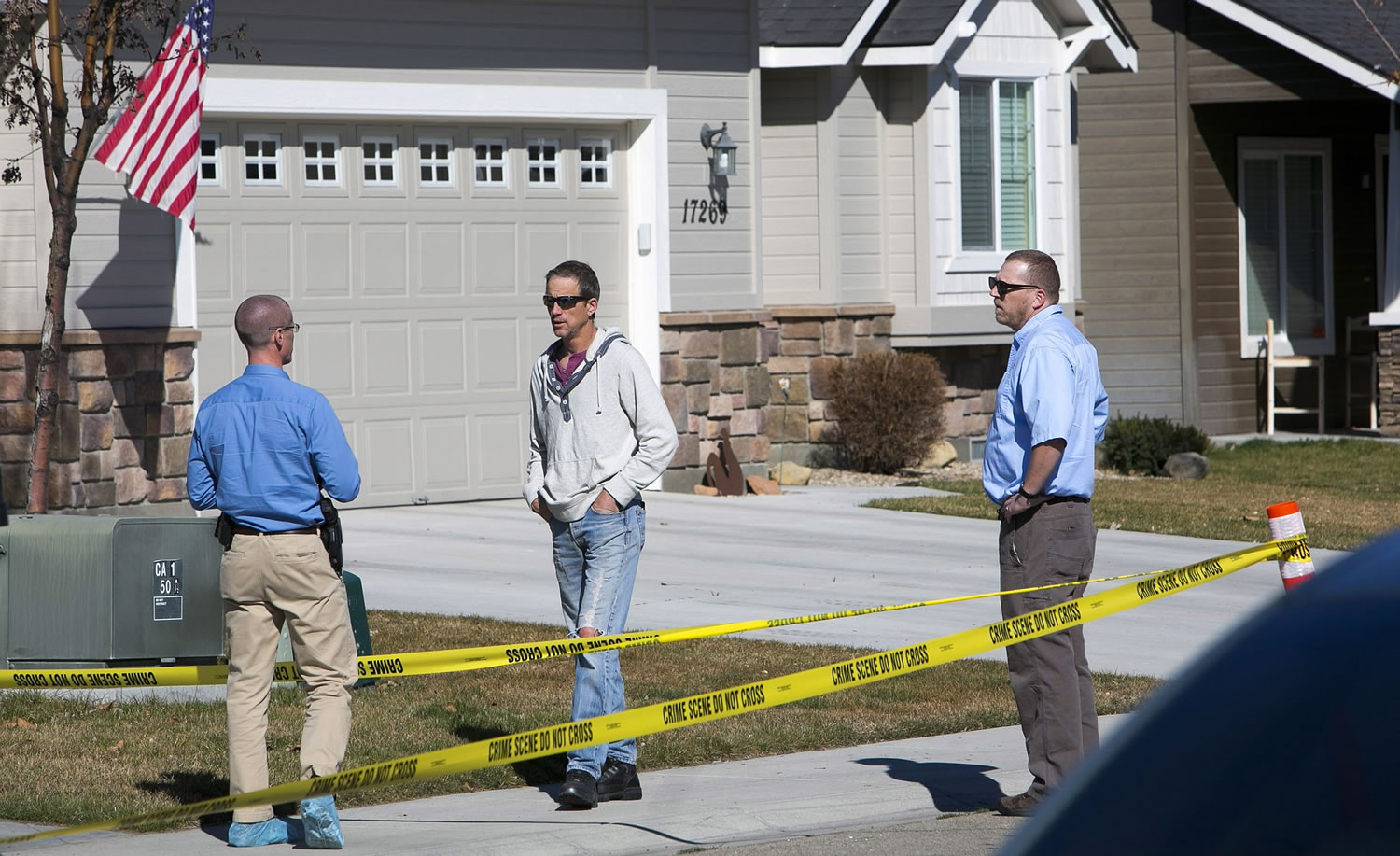 An Ada County Sheriff's Office investigator, left, talks with Adam Dees' neighbors in Nampa, Idaho.