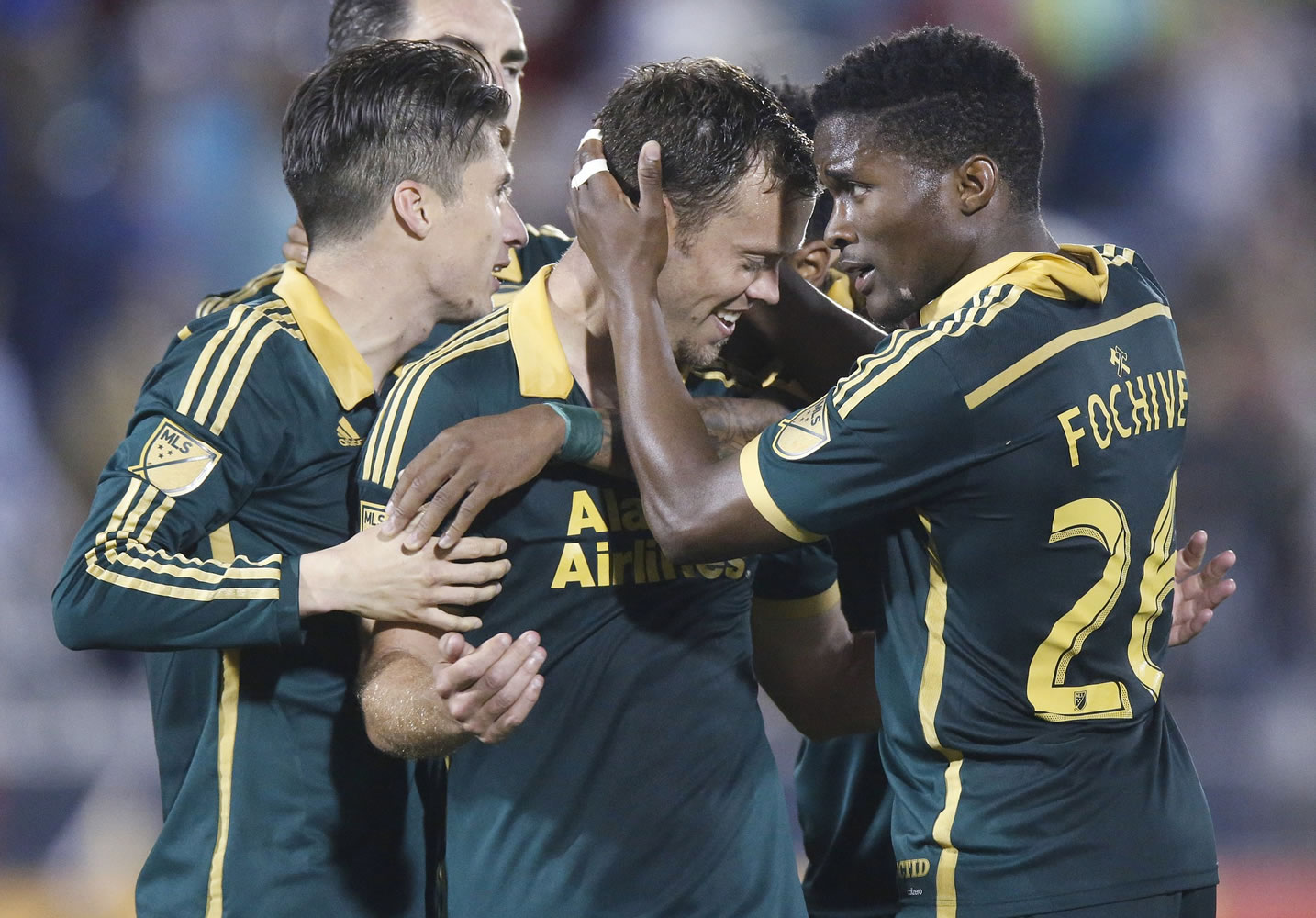 Portland Timbers midfielder Jack Jewsbury, center, is congratulated by defender Jorge Villafana, left, and midfielder George Fochive after Jewsbury scored the winning goal against the Colorado Rapids in Commerce City, Colo.