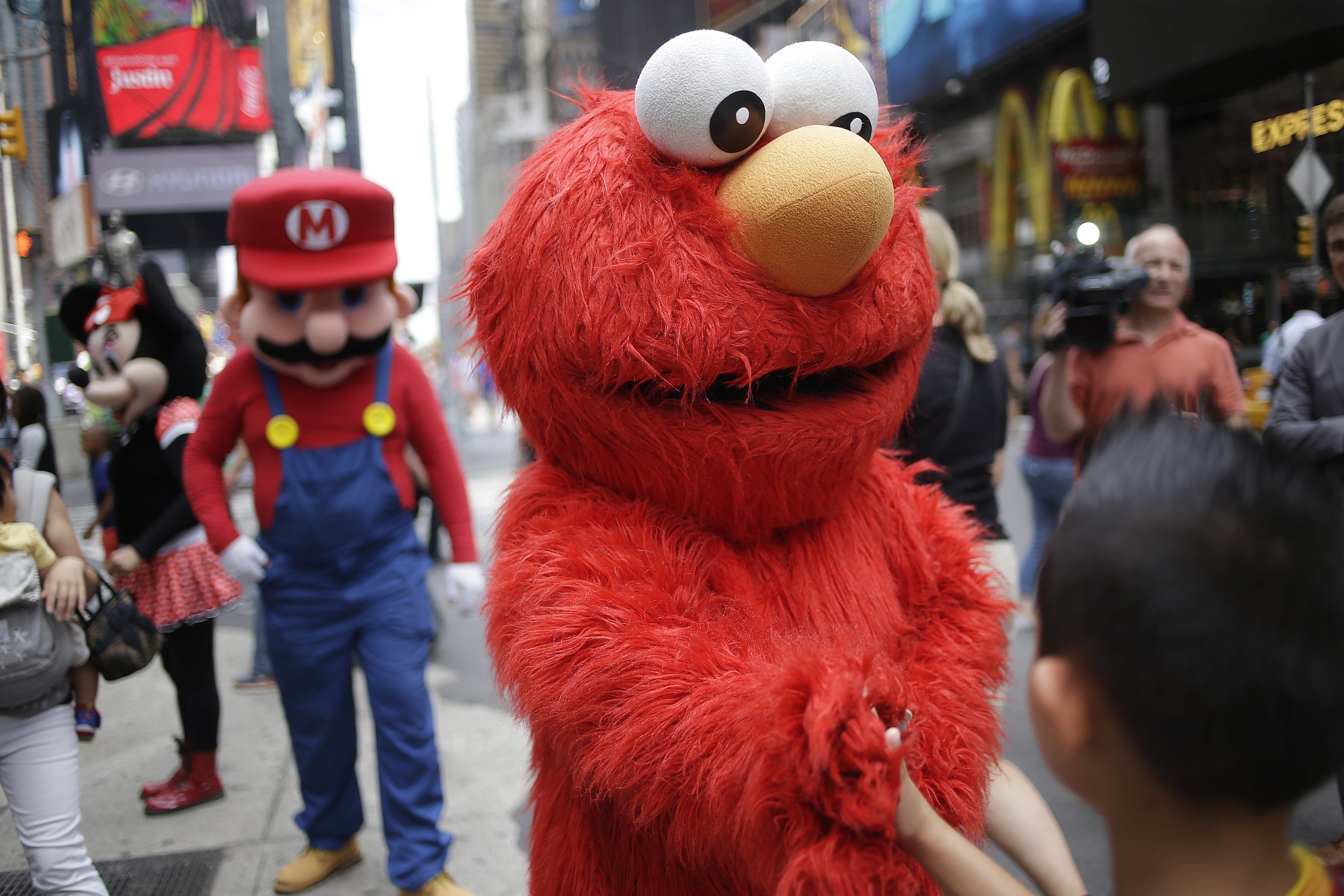 A person dressed as Elmo shakes hands with a pedestrian in Times Square on Monday in New York.