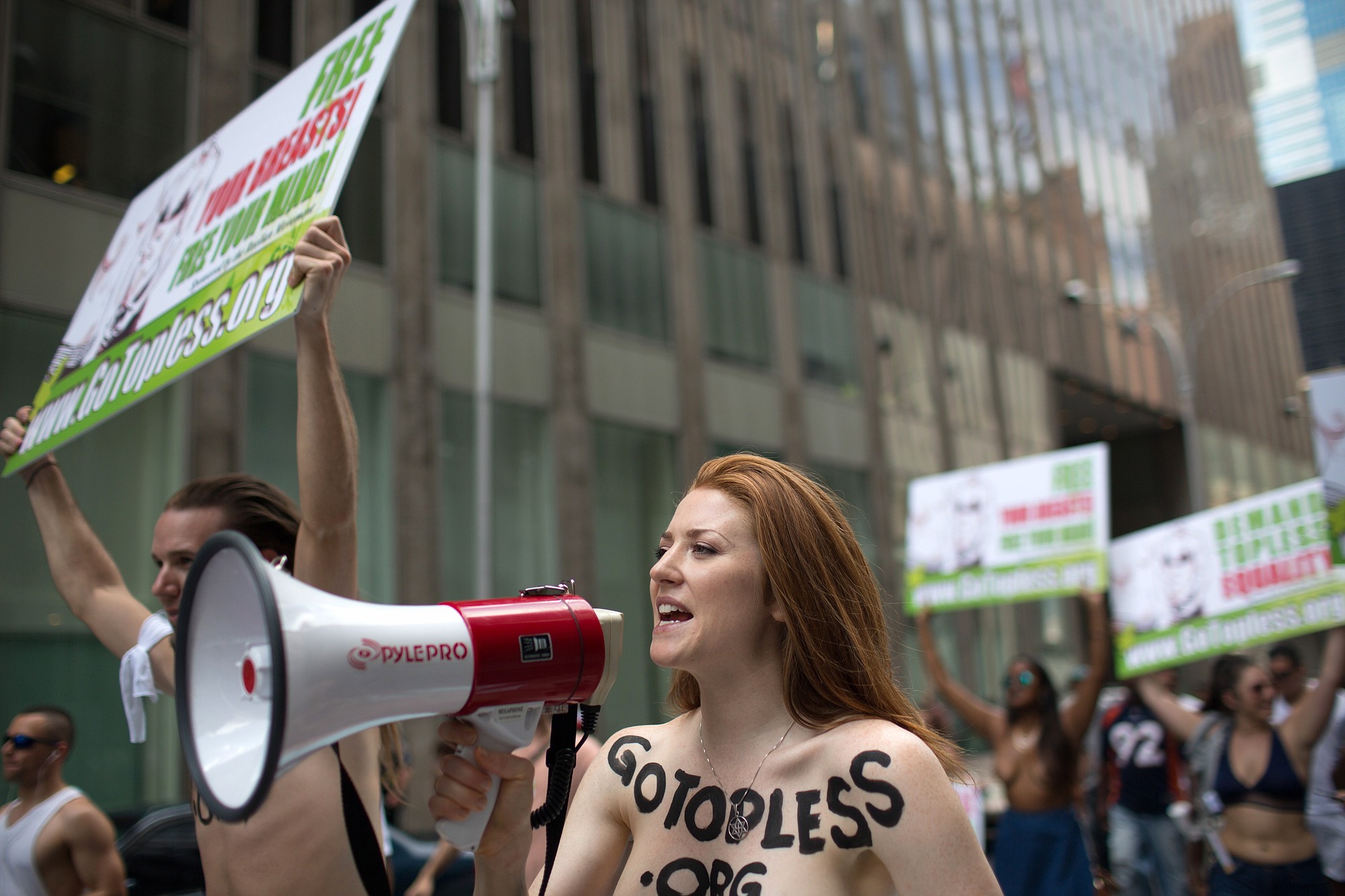 Rachel Jessee speaks into a megaphone while riding atop a car during the GoTopless Day Parade, Sunday, Aug. 23, 2015, in New York. The parade took to the streets to counter critics who are complaining about topless tip-seekers in Times Square. Appearing bare-breasted is legal in New York. But Mayor Bill de Blasio and police Commissioner Bill Bratton say the body-painted women in the square who take photos with tourists are a nuisance.