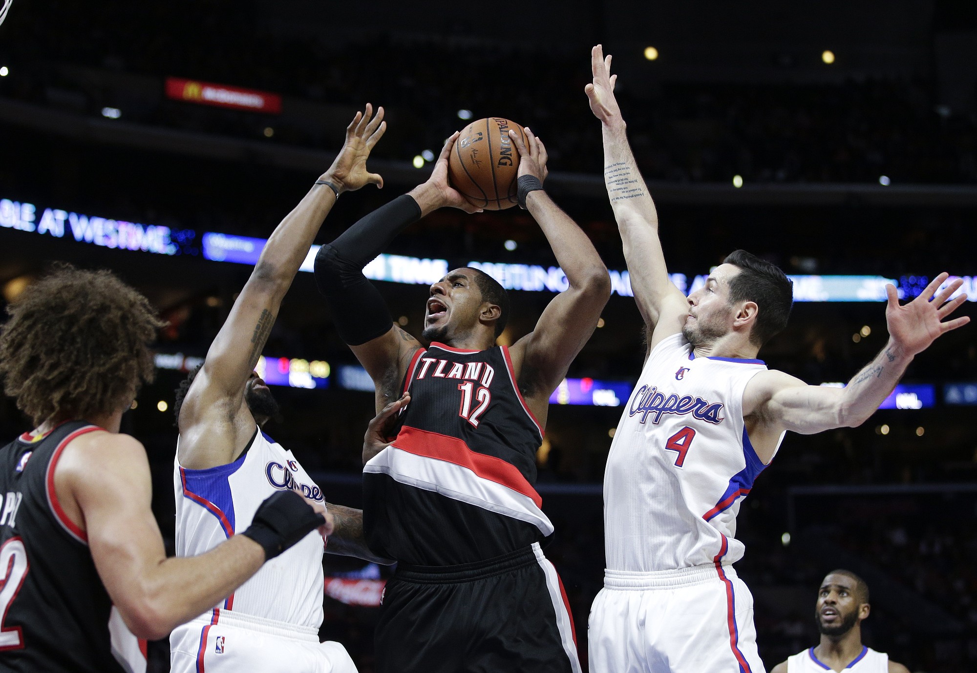 Portland Trail Blazers' LaMarcus Aldridge, center, goes up for a basket as he is defended by Los Angeles Clippers' DeAndre Jordan, left, and J.J. Redick during the second half of an NBA basketball game, Wednesday, March 4, 2015, in Los Angeles. The Trail Blazers won 98-93 in overtime. (AP Photo/Jae C.