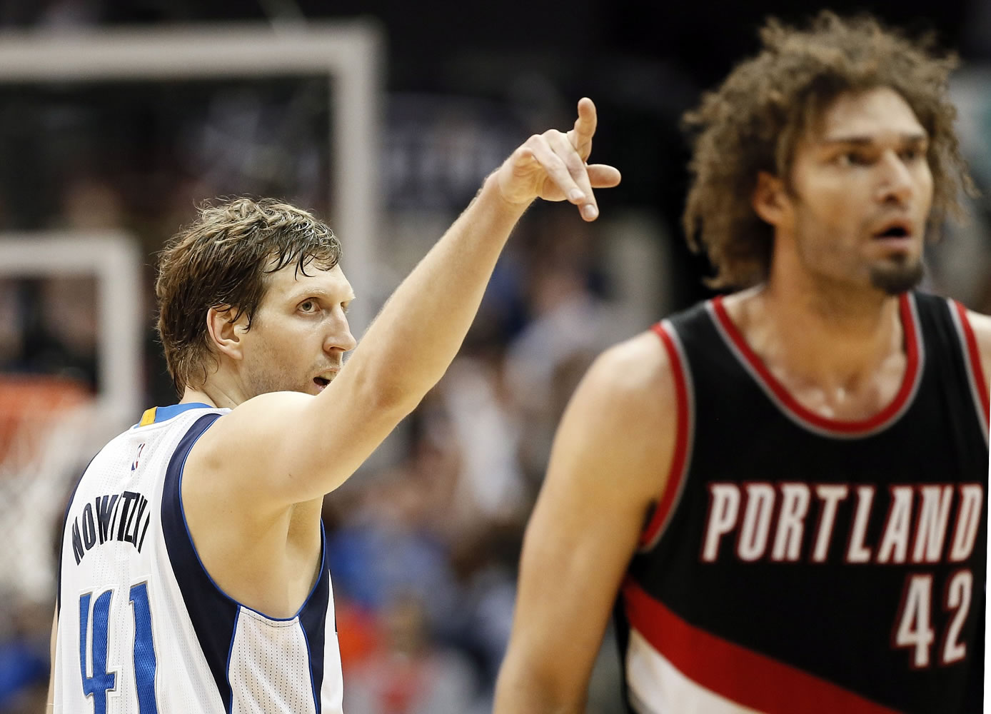 Dallas Mavericks forward Dirk Nowitzki (41), of Germany, points to the seats as Portland Trail Blazers' Robin Lopez (42) walks back to the bench after Nowitzki tied the game with a 3-point basket at the end of regulation Saturday, Feb. 7, 2015, in Dallas. The Mavericks won in overtime 111-101.