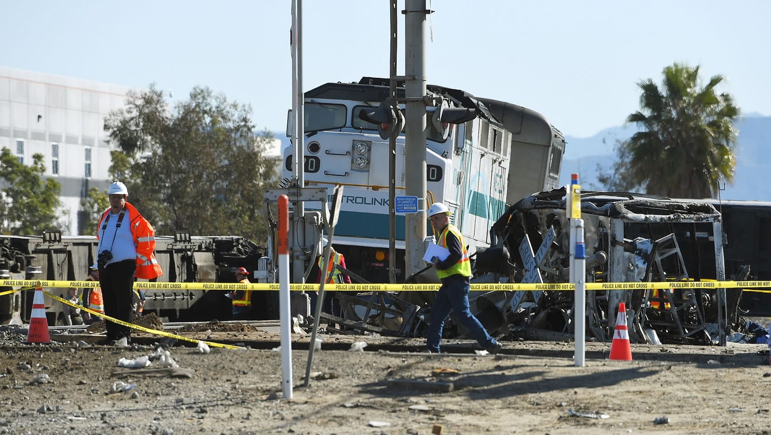 Workers walk near a Metrolink train engine from a train that hit a truck and then derailed Tuesday in Oxnard, Calif.