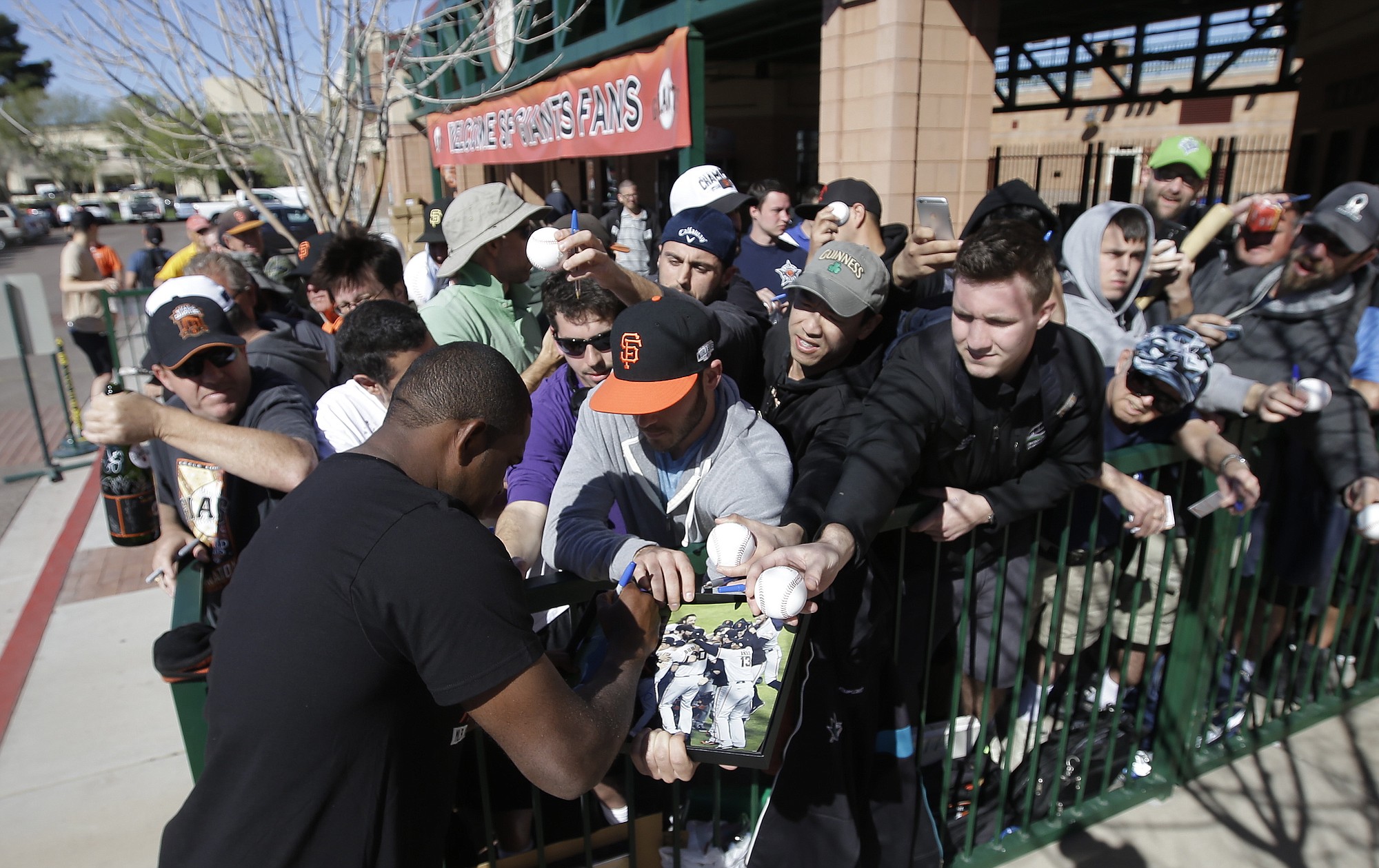 San Francisco Giants' Santiago Casilla signs autographs for fans after arriving for spring training baseball workouts in Scottsdale, Ariz.