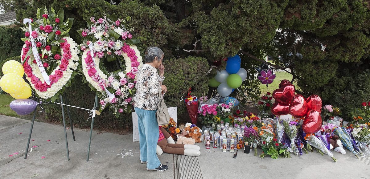 A woman visits the street-side memorial Saturday at North Jacaranda Street and Fairhaven Avenue in Santa Ana, Calif., where three teenage trick-or-treaters were killed in a Friday night hit-and-run crash.