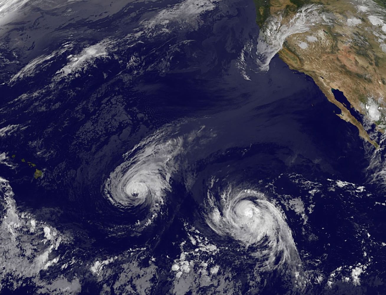 This image provided by NOAA taken Wednesday  shows Hurricane Iselle, center, and tropical storm Julio, right. Though it's not clear how damaging the storms could be, many in Hawaii aren't taking any chances as they wait for Hurricane Iselle to make landfall later this week and Tropical Storm Julio potentially hitting a few days later.