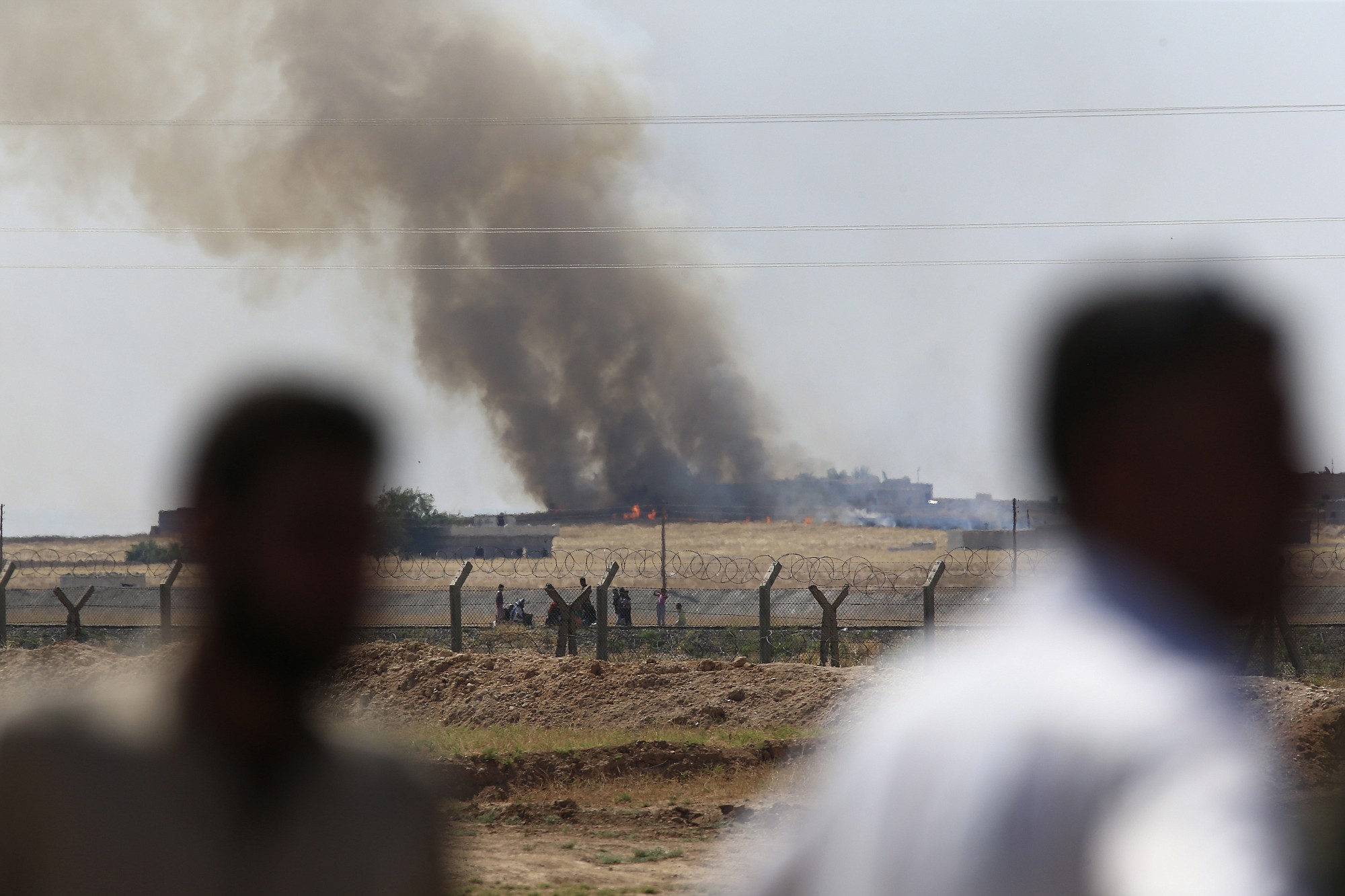 In this photo taken from the Turkish side of the border between Turkey and Syria, in Akcakale, southeastern Turkey, people watch as smoke from a US-led airstrike rises over the outskirts of Tal Abyad, Syria, on Monday.
